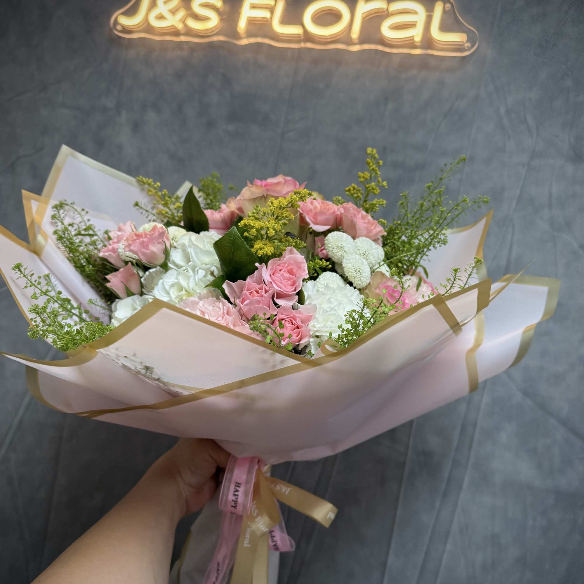 Pink and white bouquet of roses and carnations wrapped in pale paper