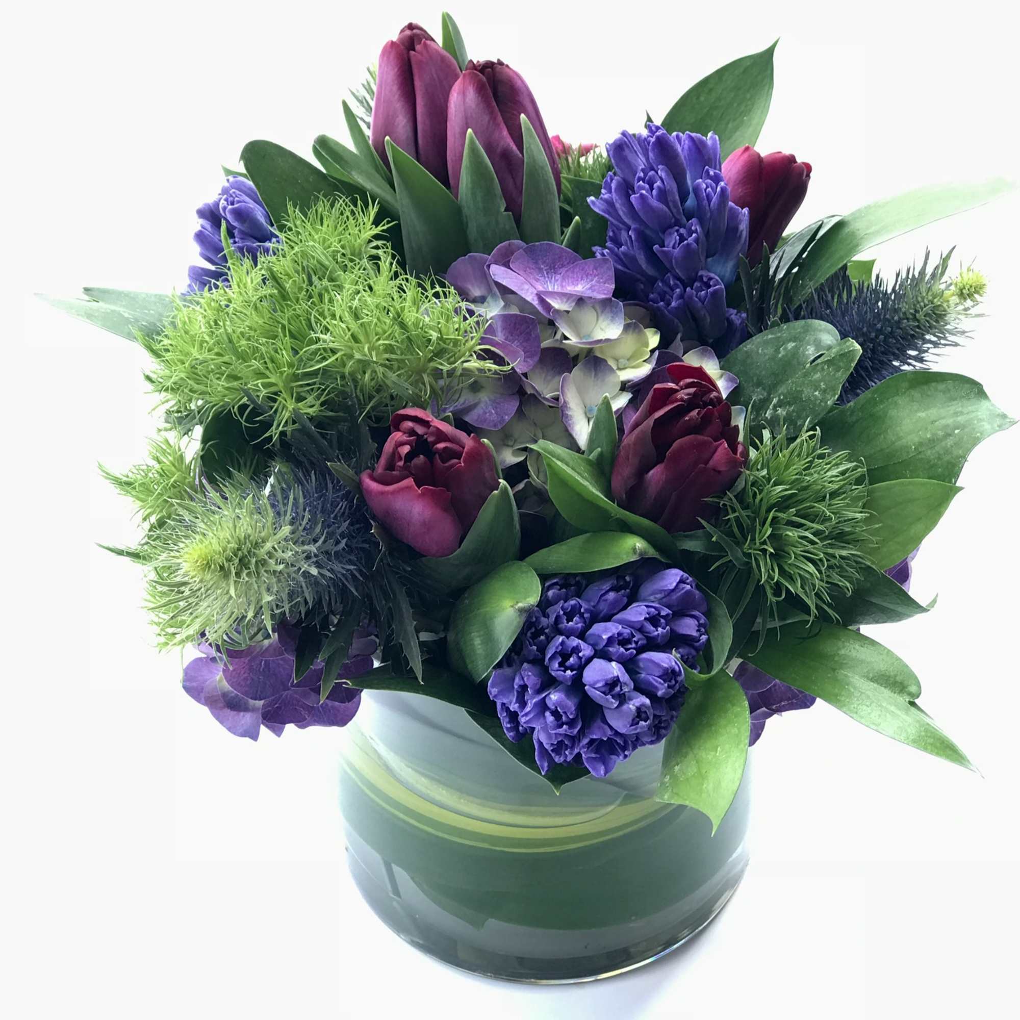 Purple and burgundy flowers arranged in a glass vase