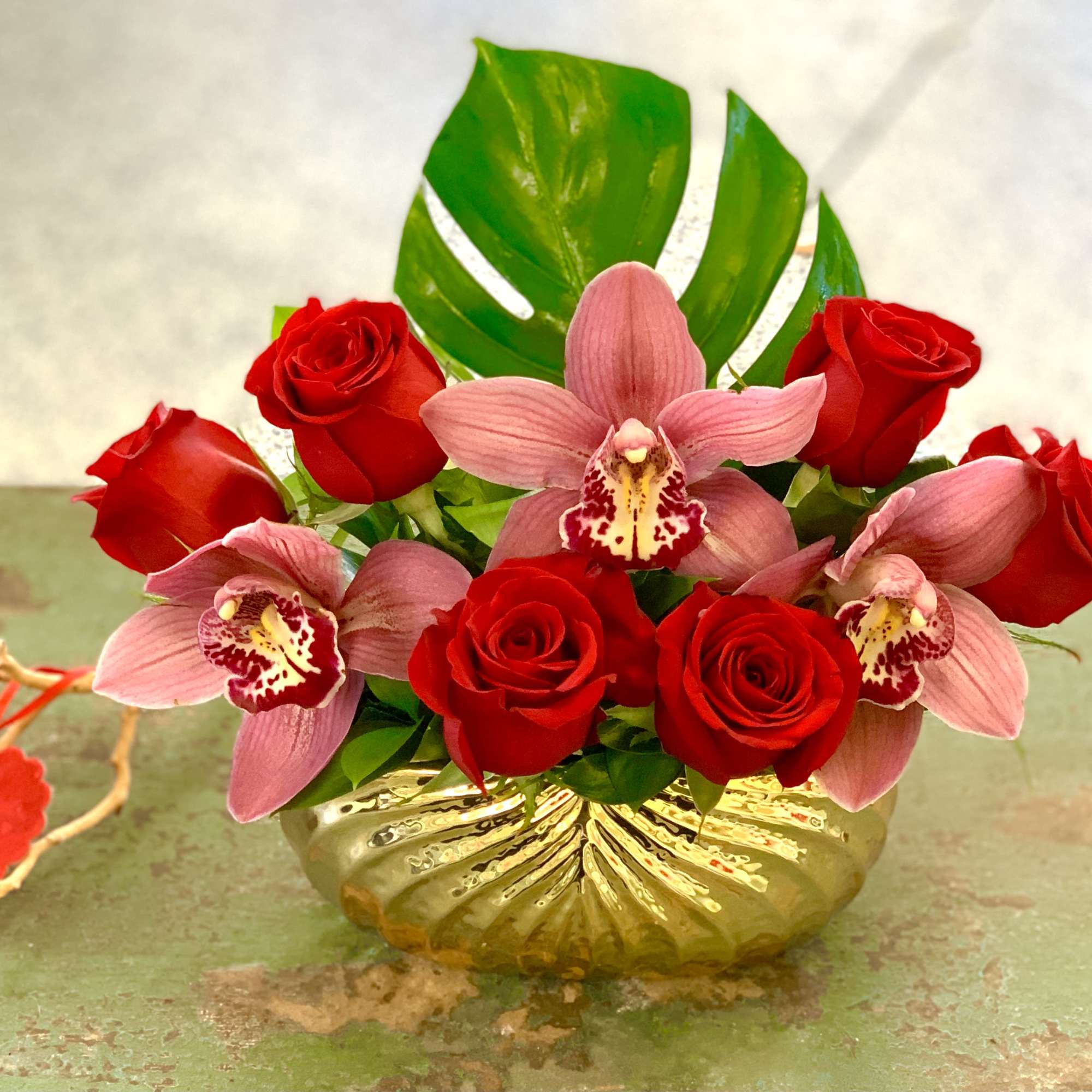 Red roses and pink orchids arranged in a gold vase