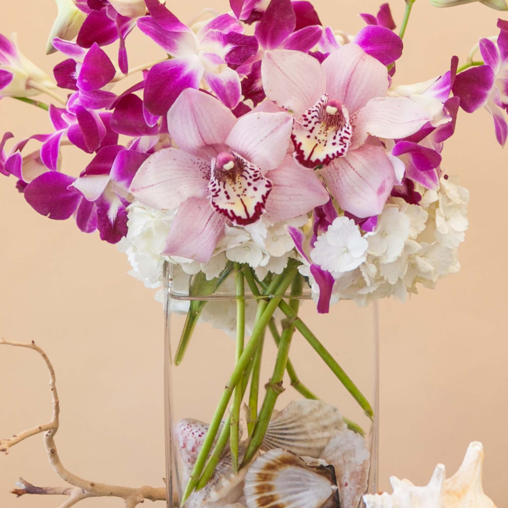 Pink and purple orchids in a clear glass vase with white flowers