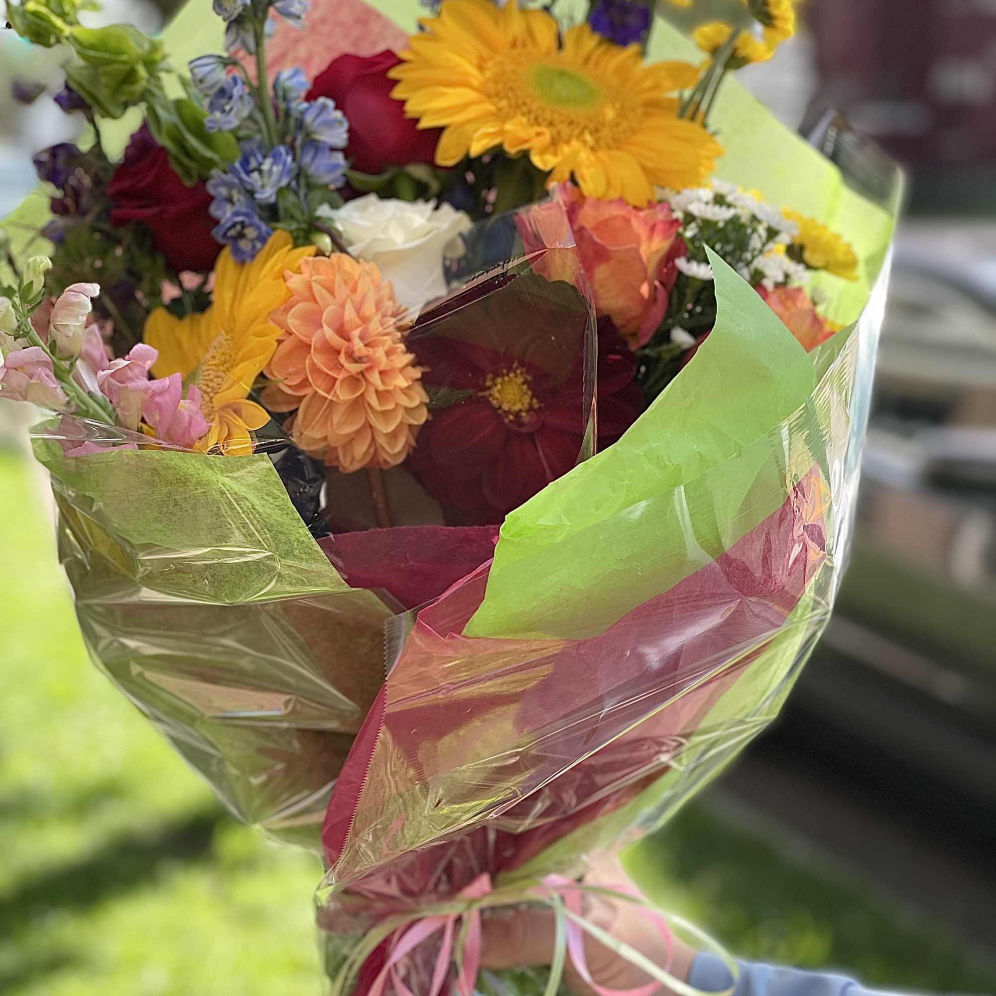 Mixed bouquet with bright gerbera daisies, roses, and snapdragons wrapped in colorful paper