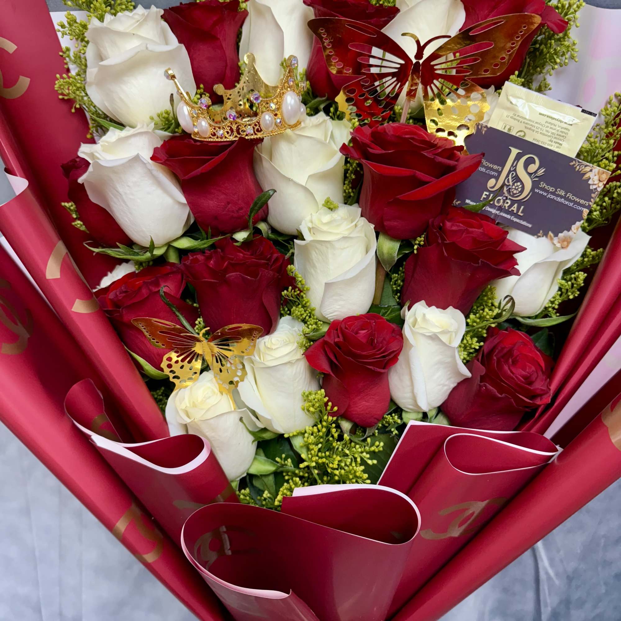 Bouquet of red and white roses with decorative butterflies and a crown