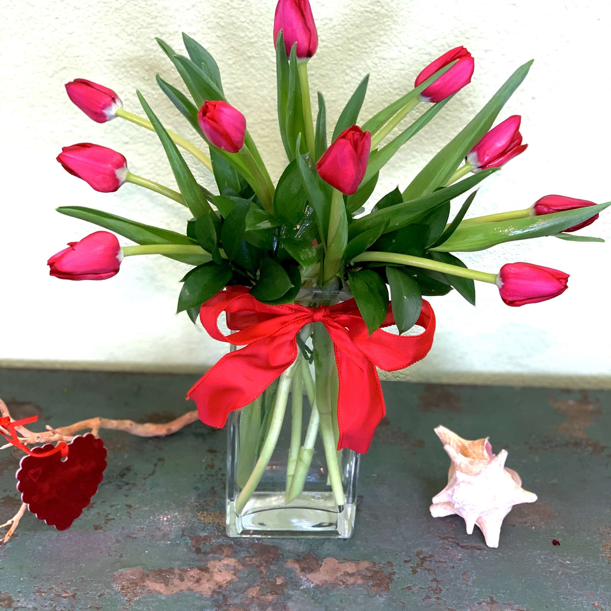 Pink tulips arranged in a clear glass vase with a red ribbon