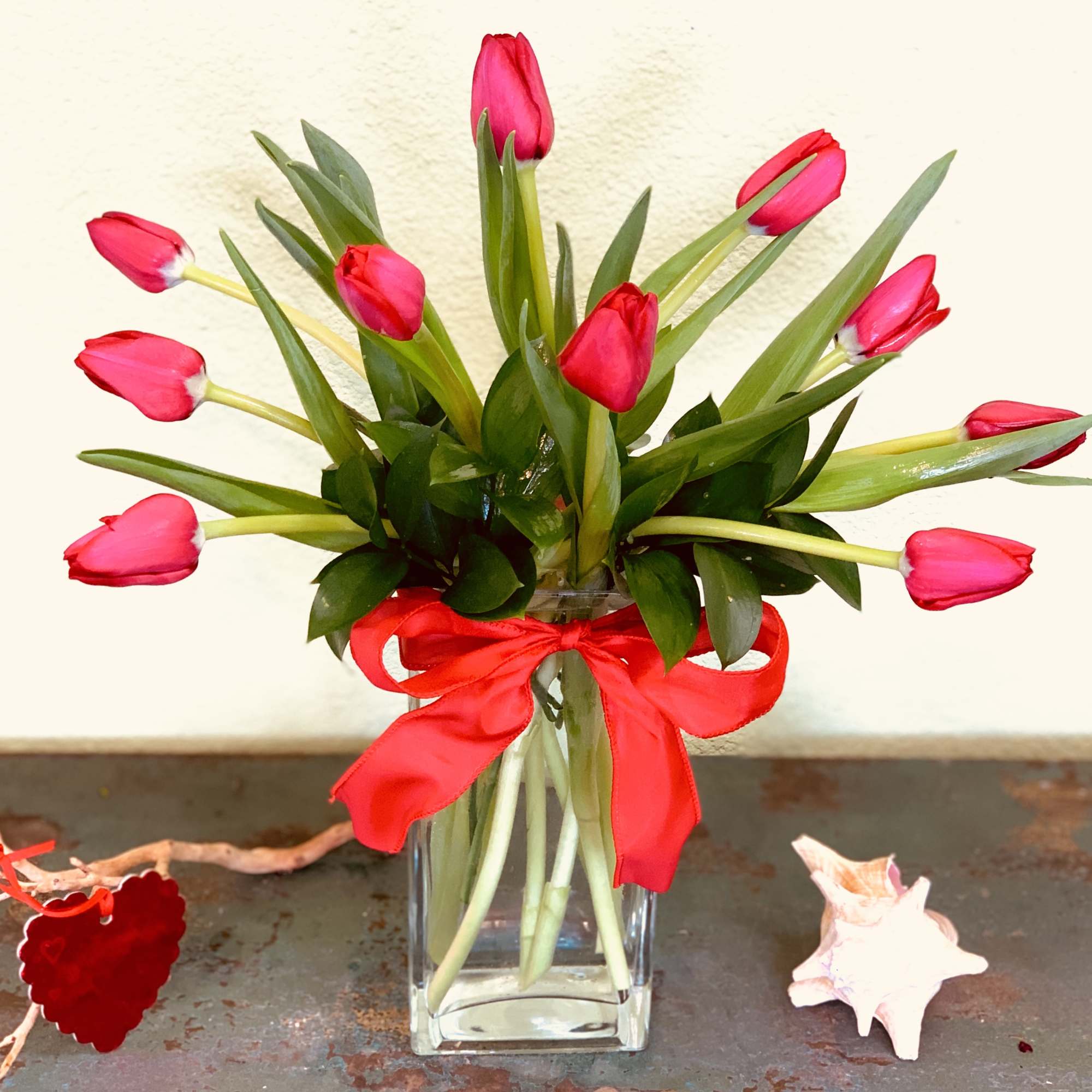 Pink tulips arranged in a clear glass vase with a red ribbon