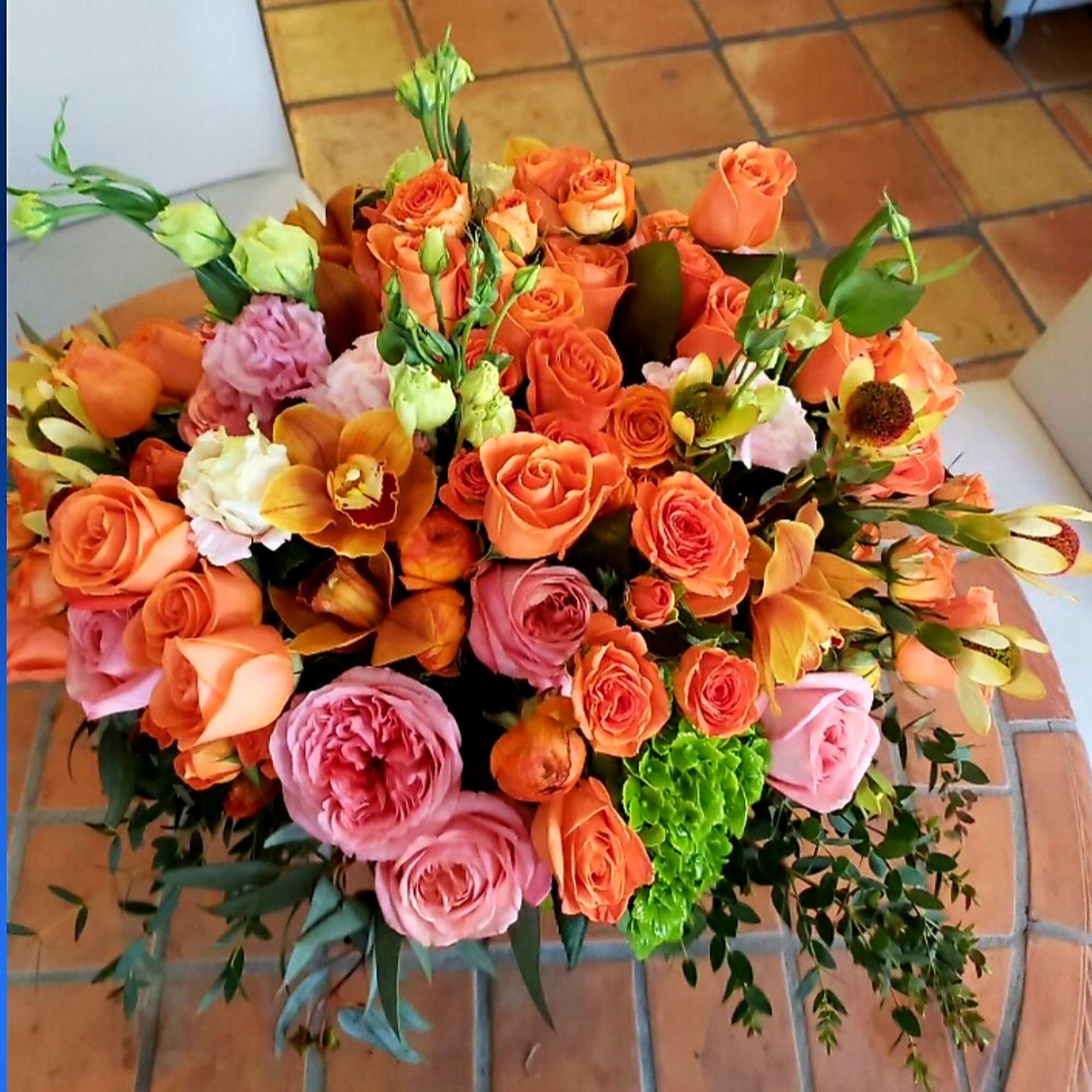 Large bouquet of orange and pink roses with mixed blooms