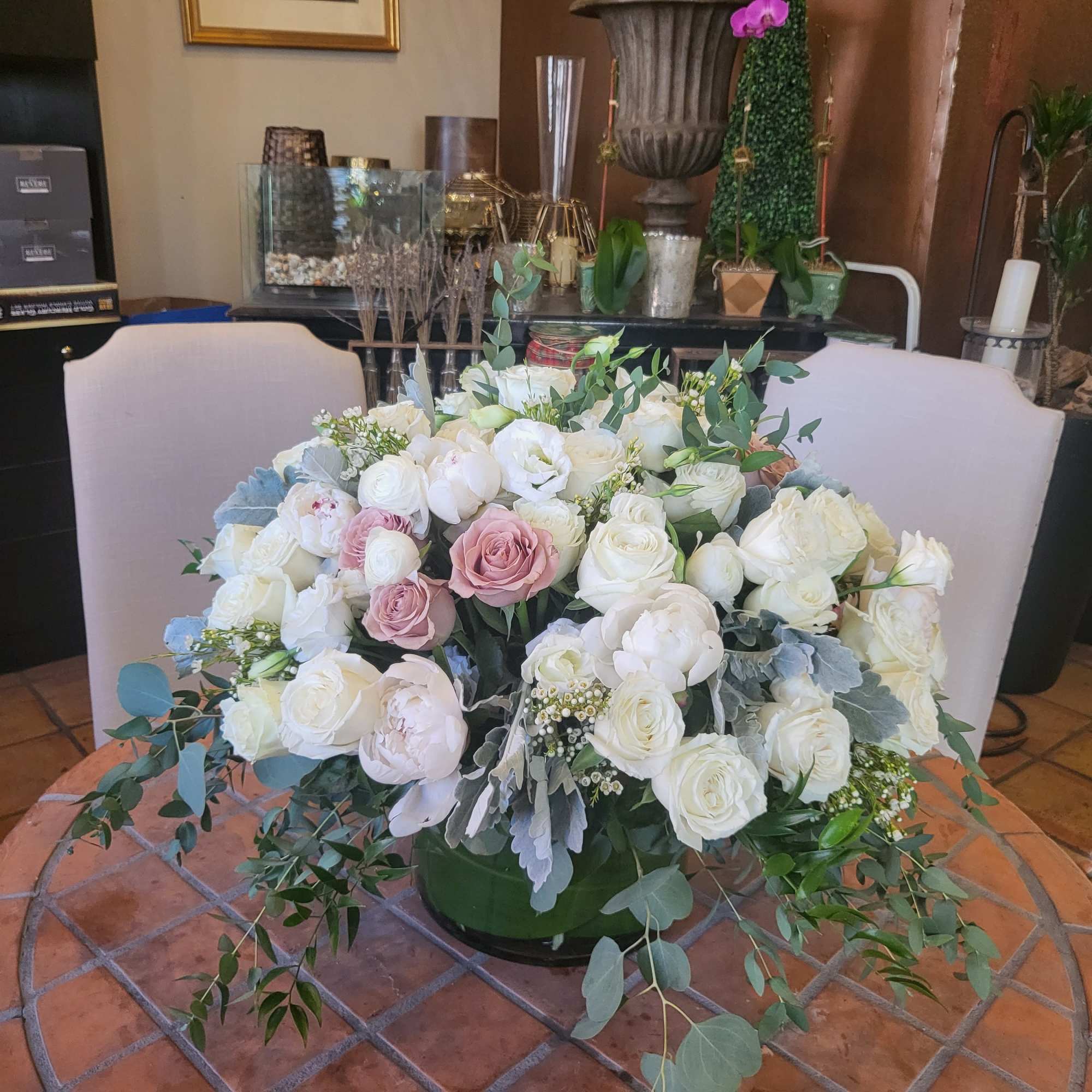 Large bouquet of white and blush roses with eucalyptus in a green container