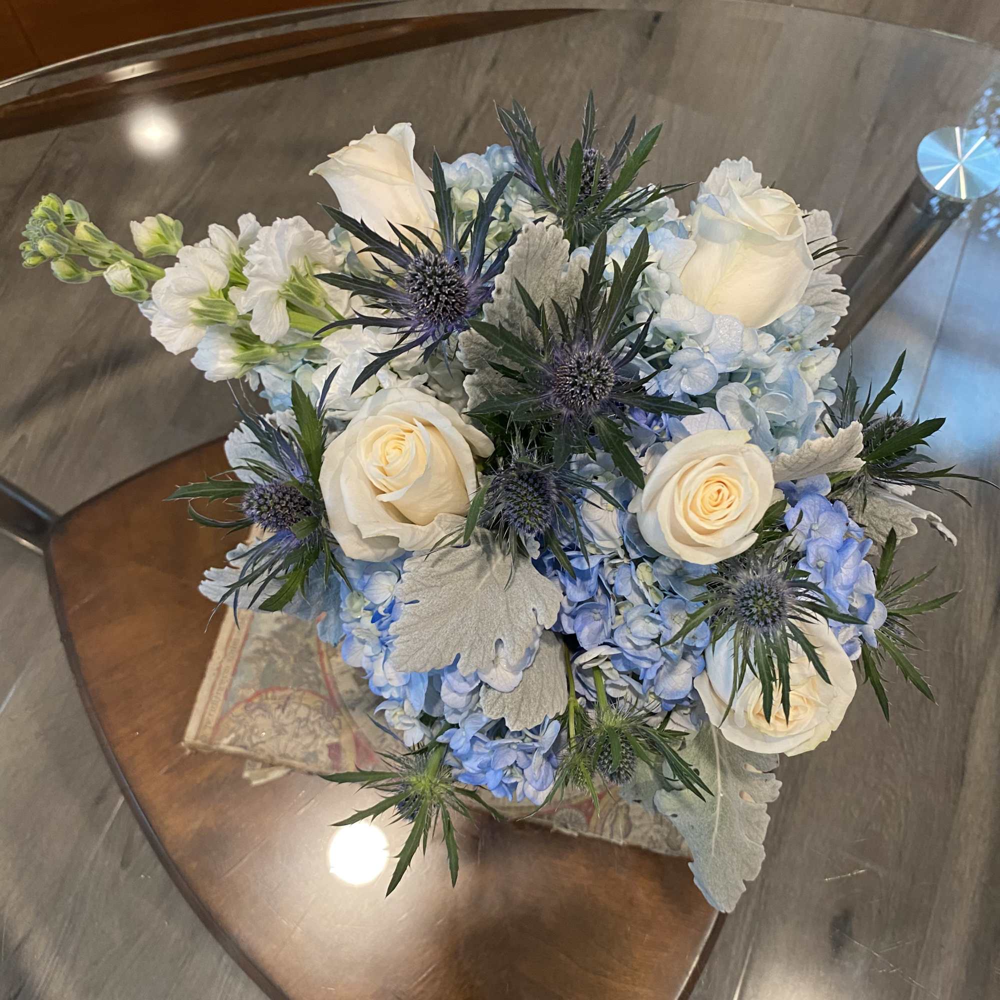 Bouquet of white roses and blue hydrangeas with spiky thistle flowers