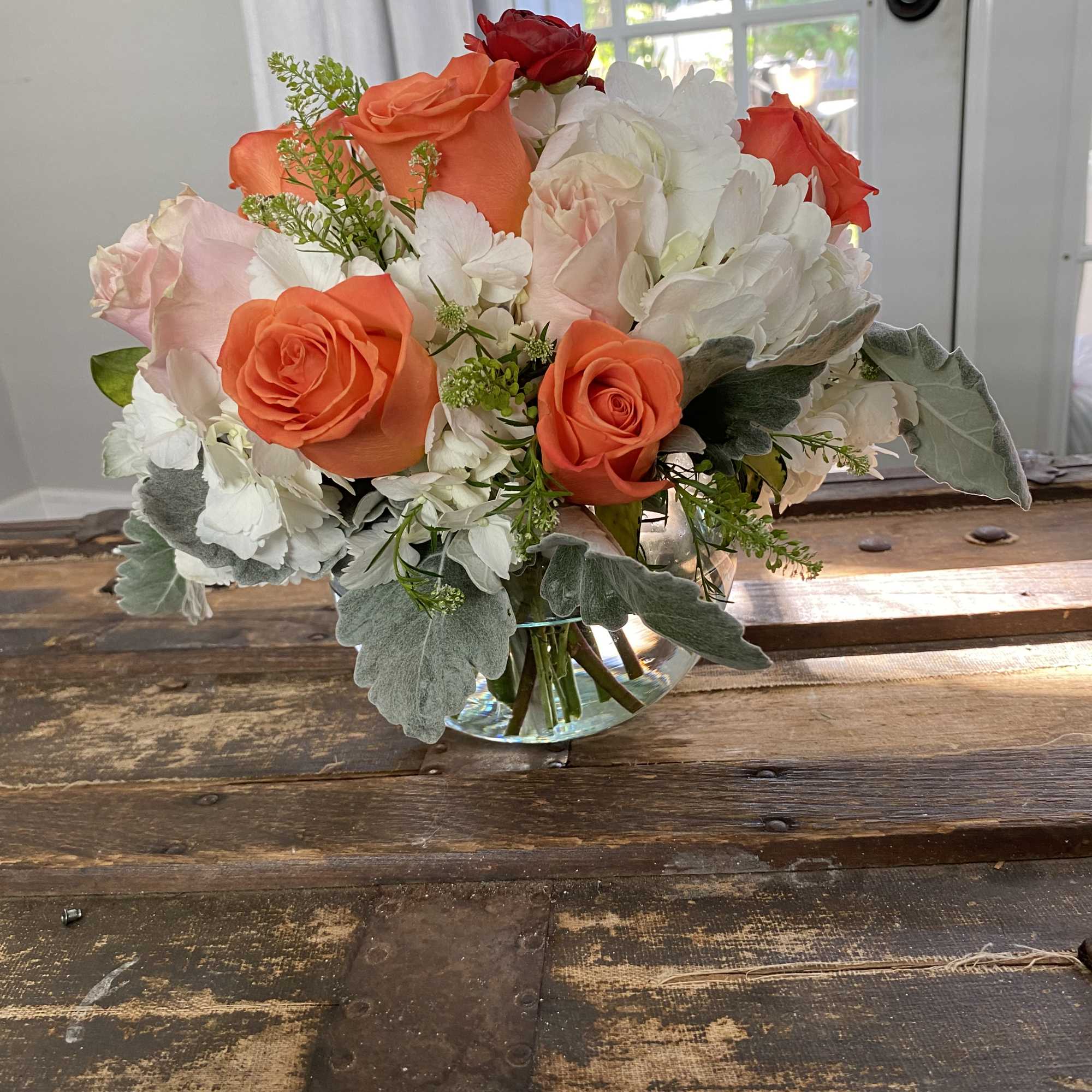 Bouquet of orange and white roses in a clear glass vase