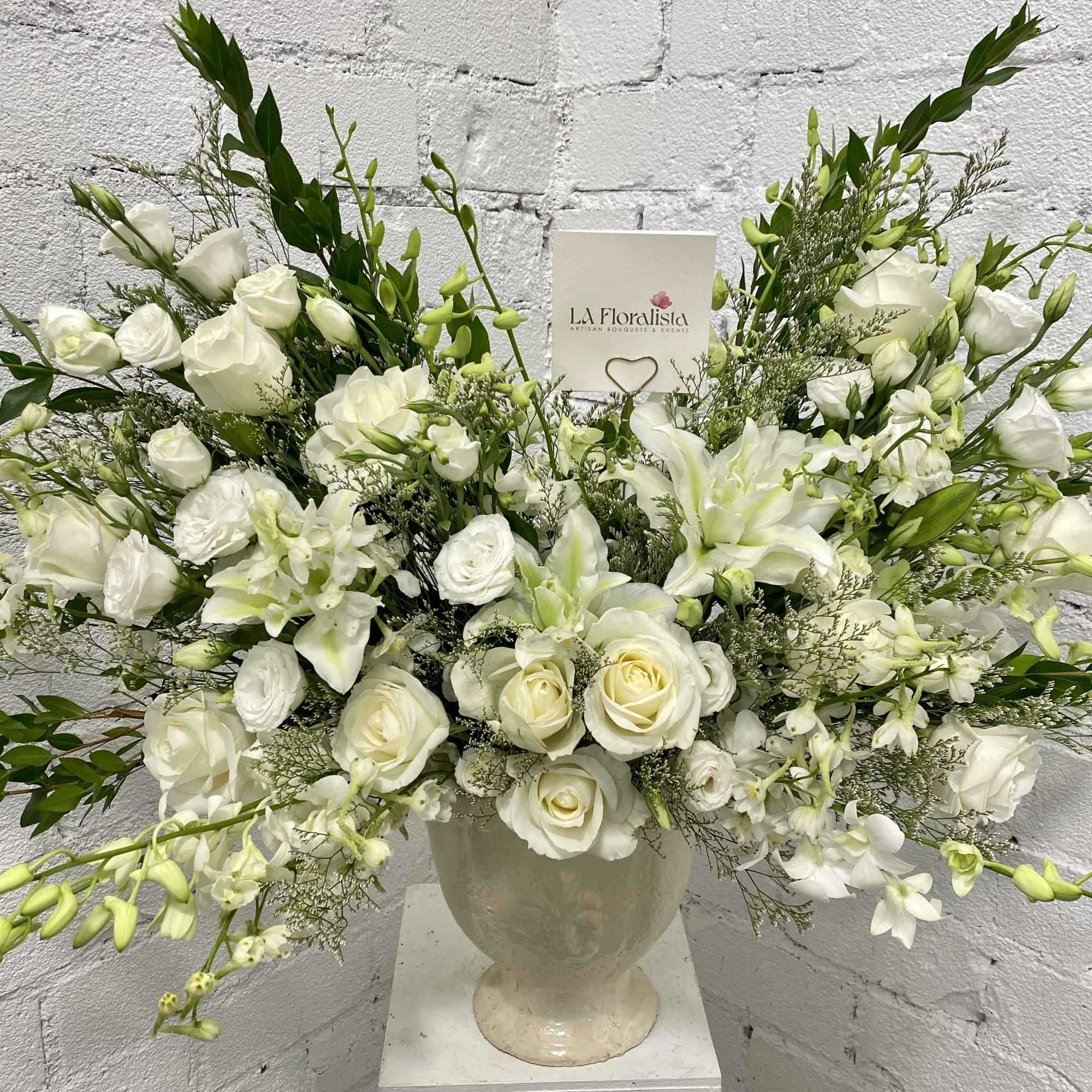 White floral arrangement in a cream urn vase