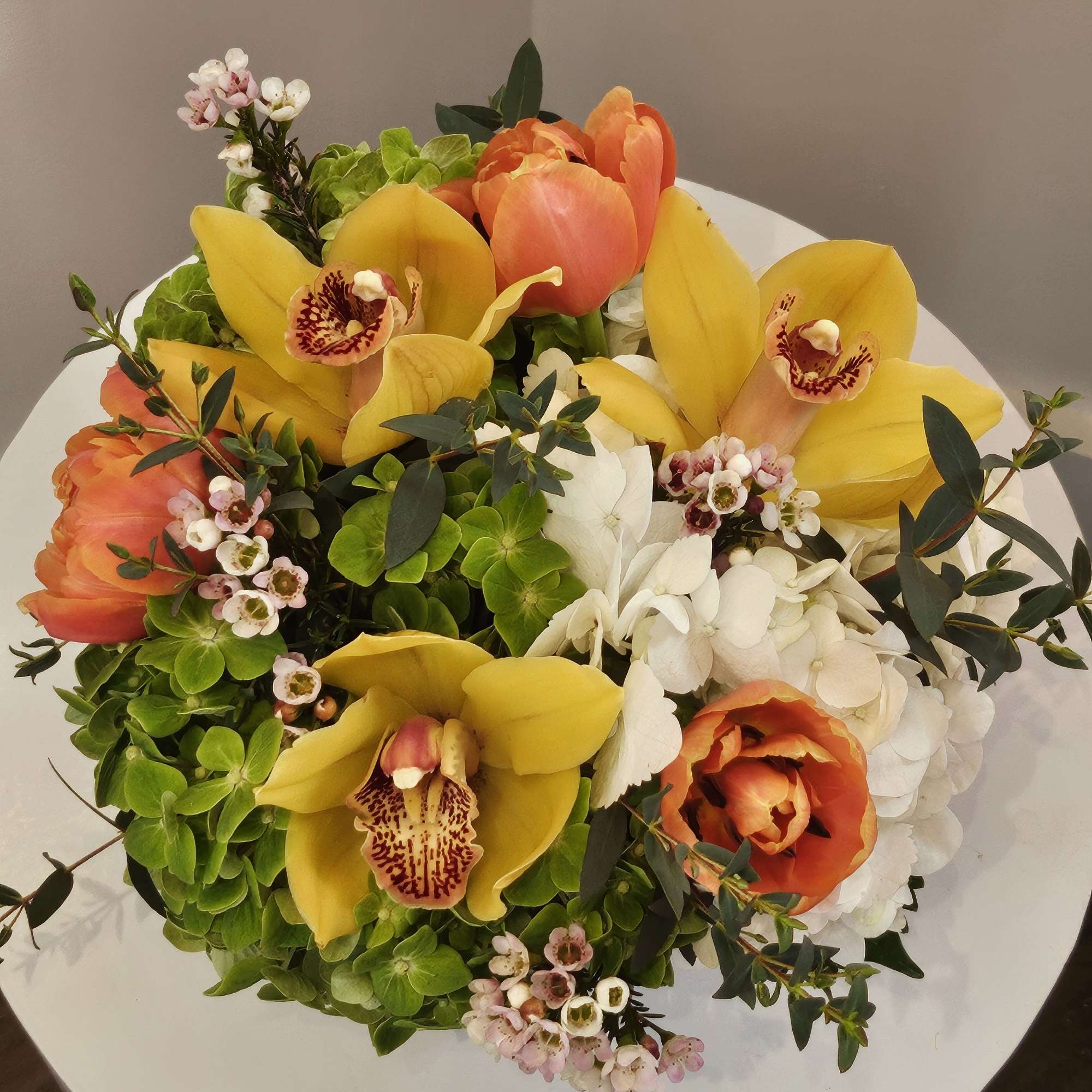 Bouquet of yellow orchids, orange tulips, and white hydrangeas