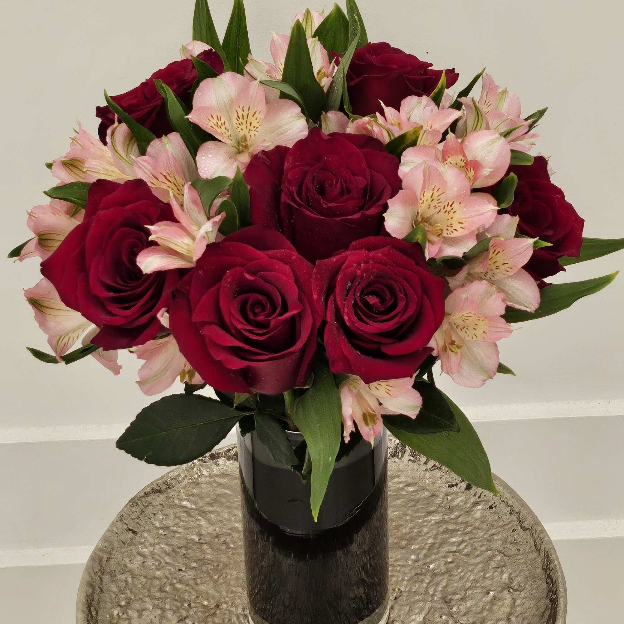 Bouquet of red roses and pink alstroemeria in a black vase