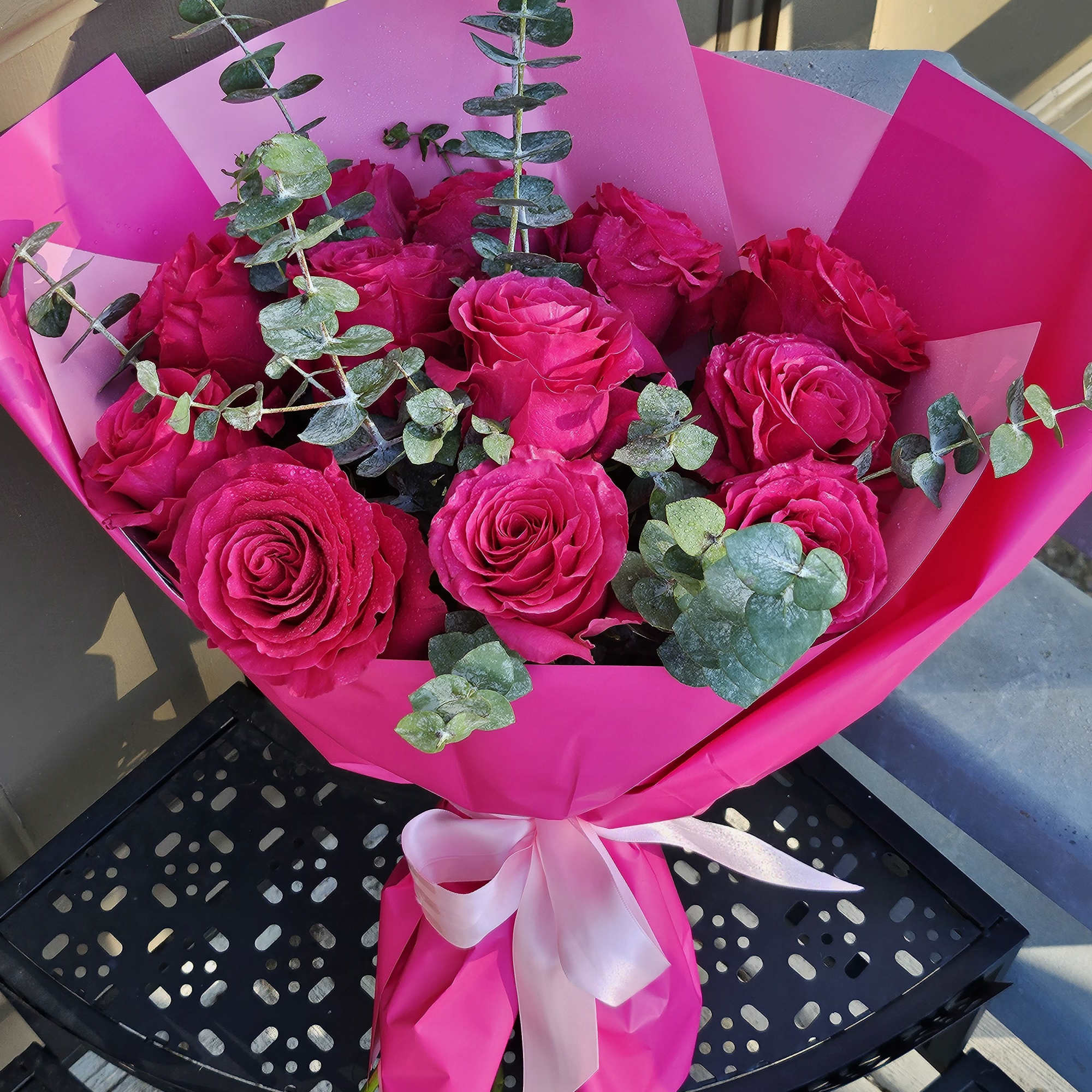 Bouquet of hot pink roses wrapped in bright pink paper with a ribbon