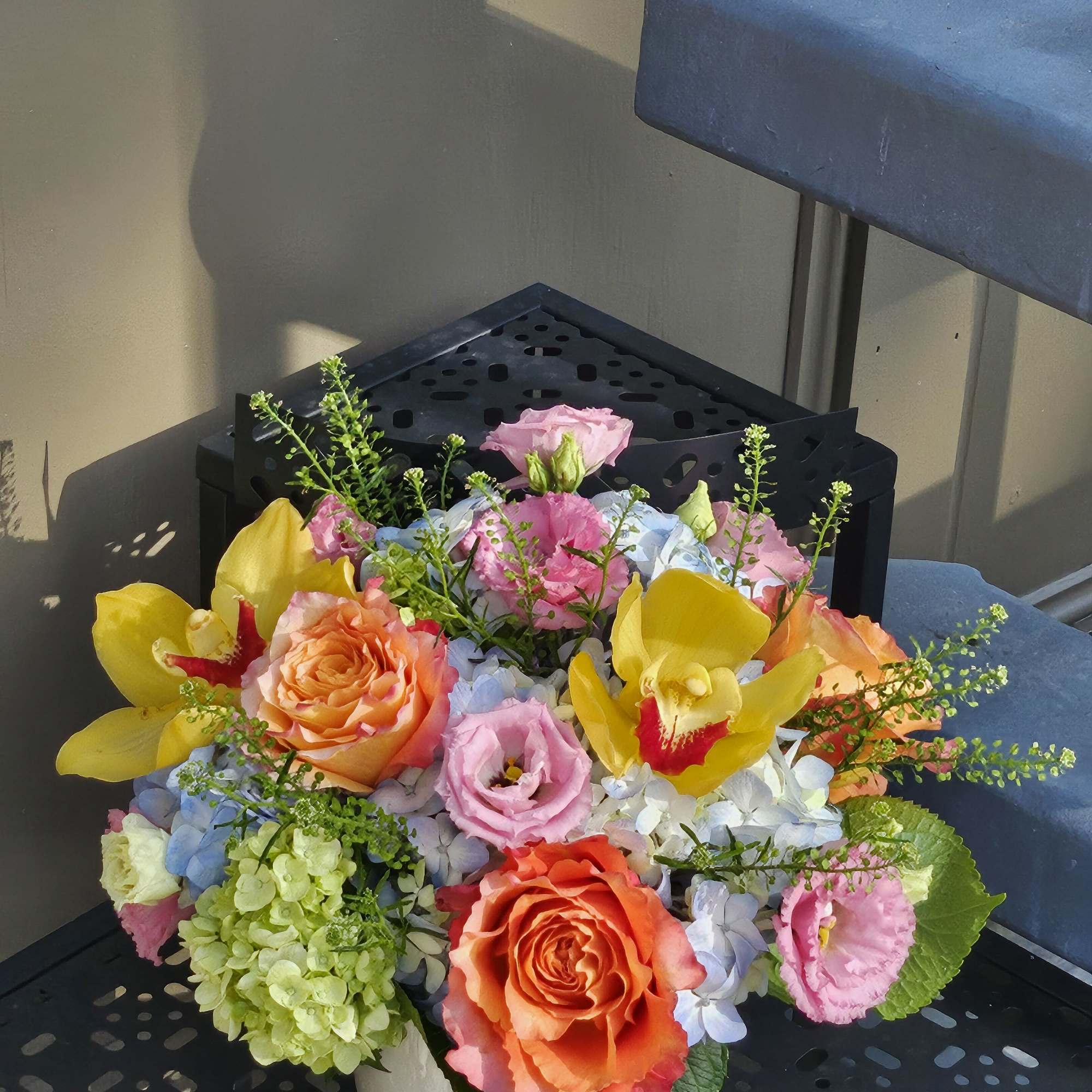 Colorful bouquet of roses, orchids, hydrangeas, and lisianthus in a white bowl