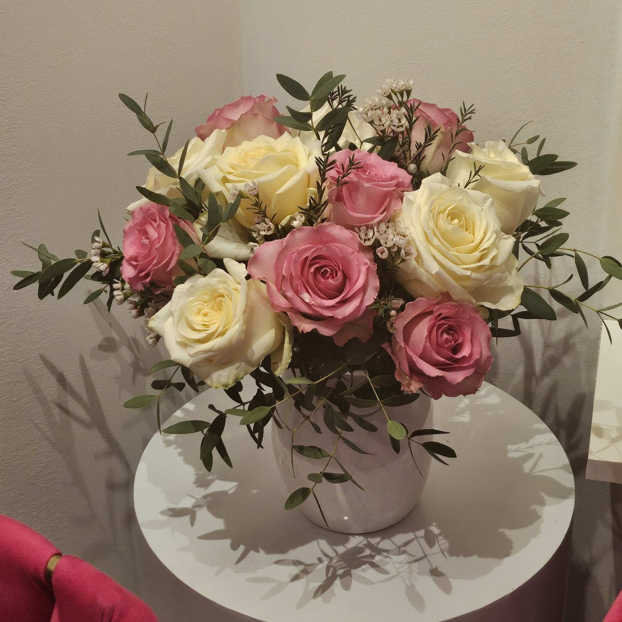 Pink and cream roses arranged in a white vase