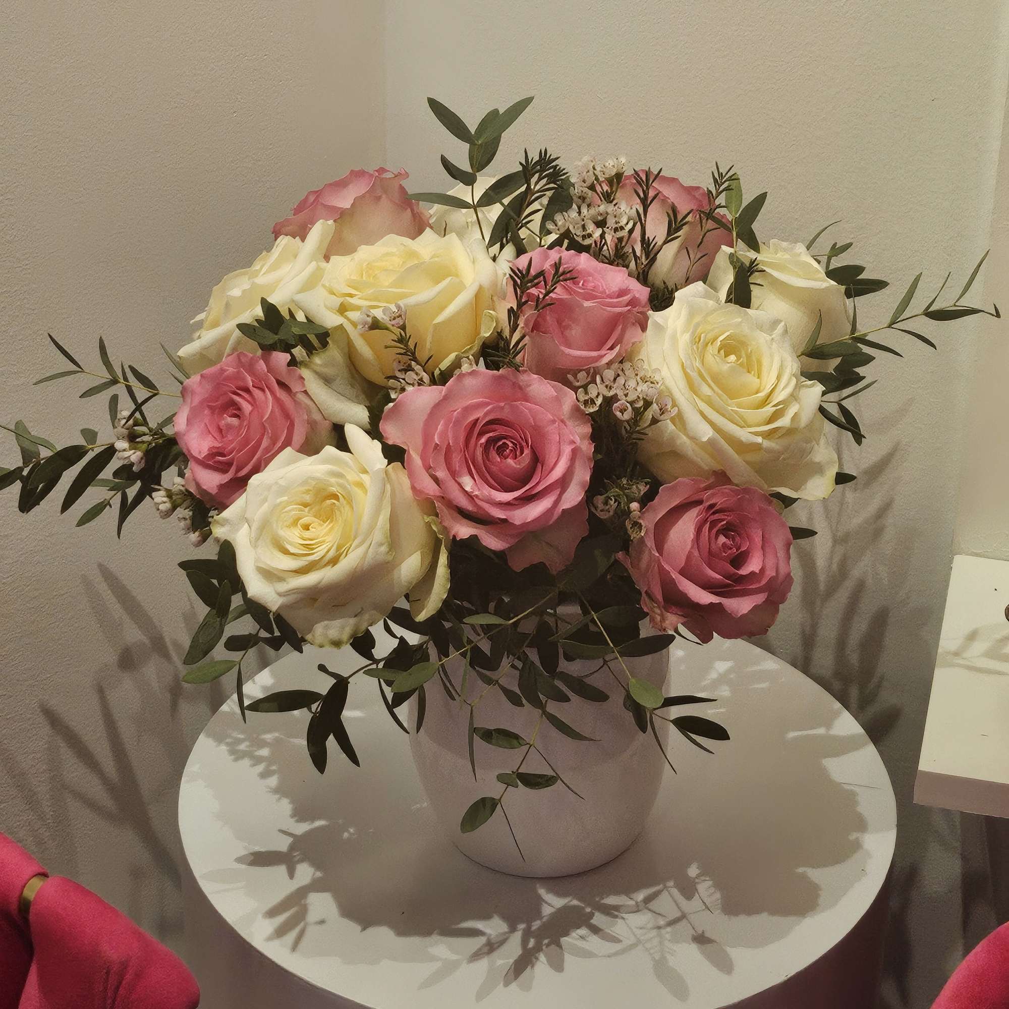 Pink and cream roses arranged in a white vase