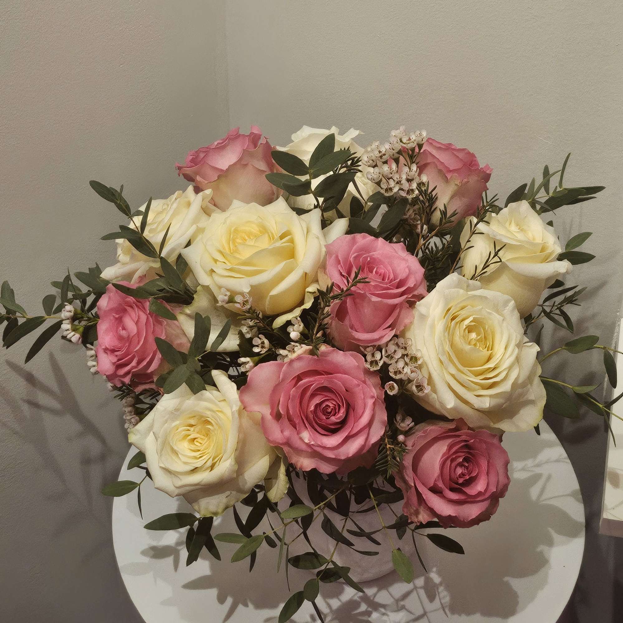 Bouquet of pink and cream roses with greenery on a round table