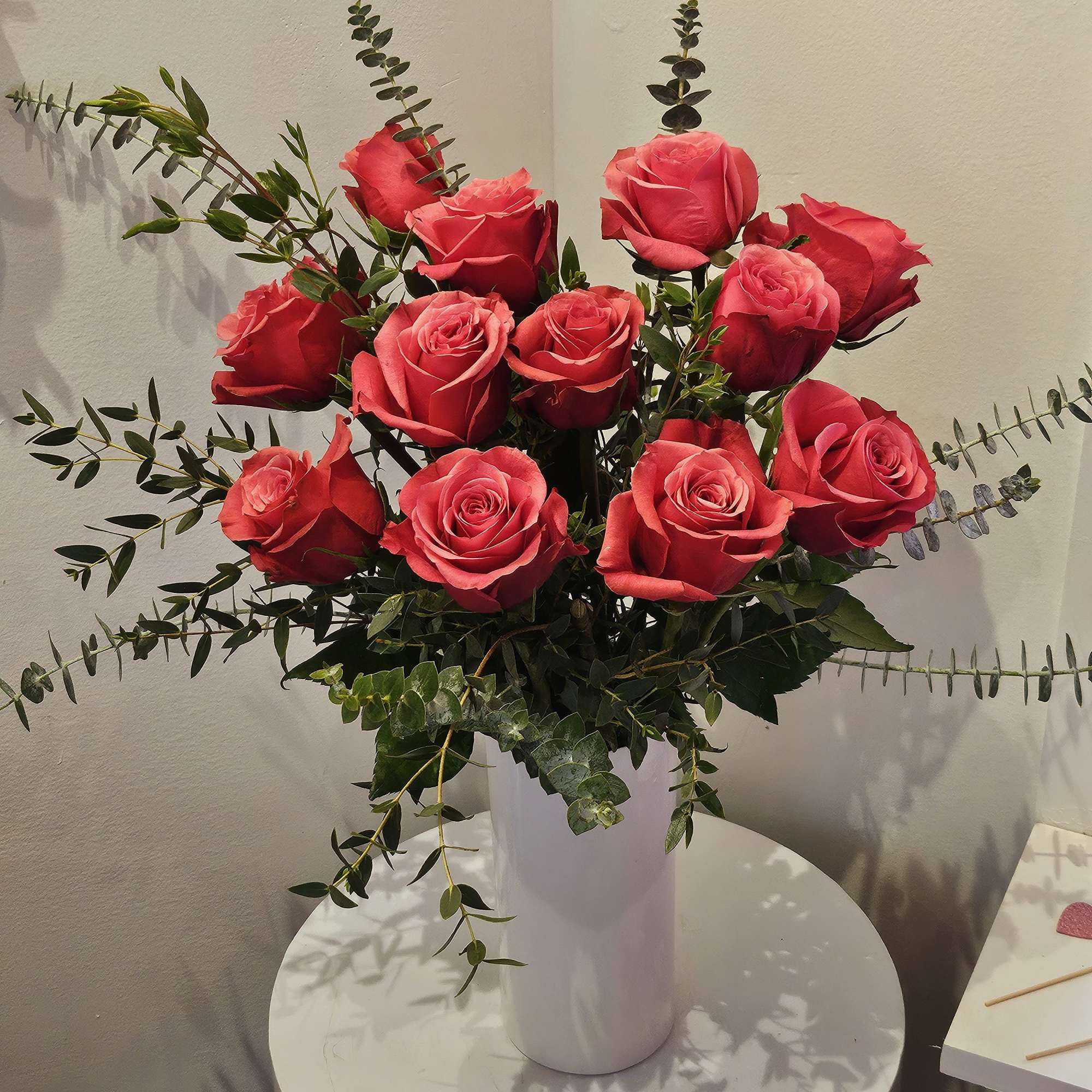 Pink rose bouquet in a white vase with eucalyptus