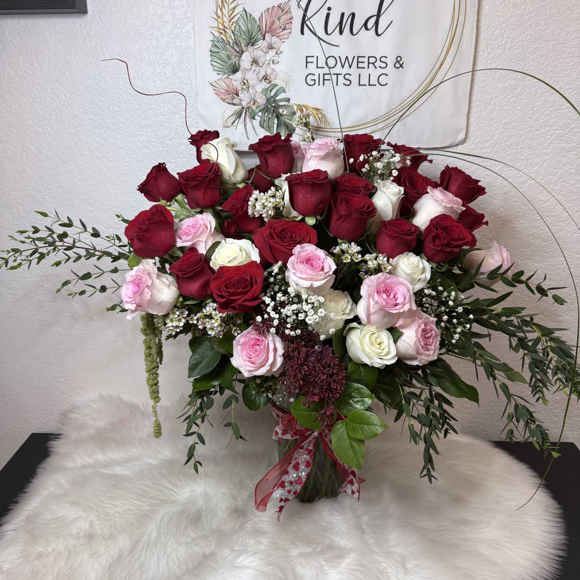 Large bouquet of red, pink, and white roses in a glass vase