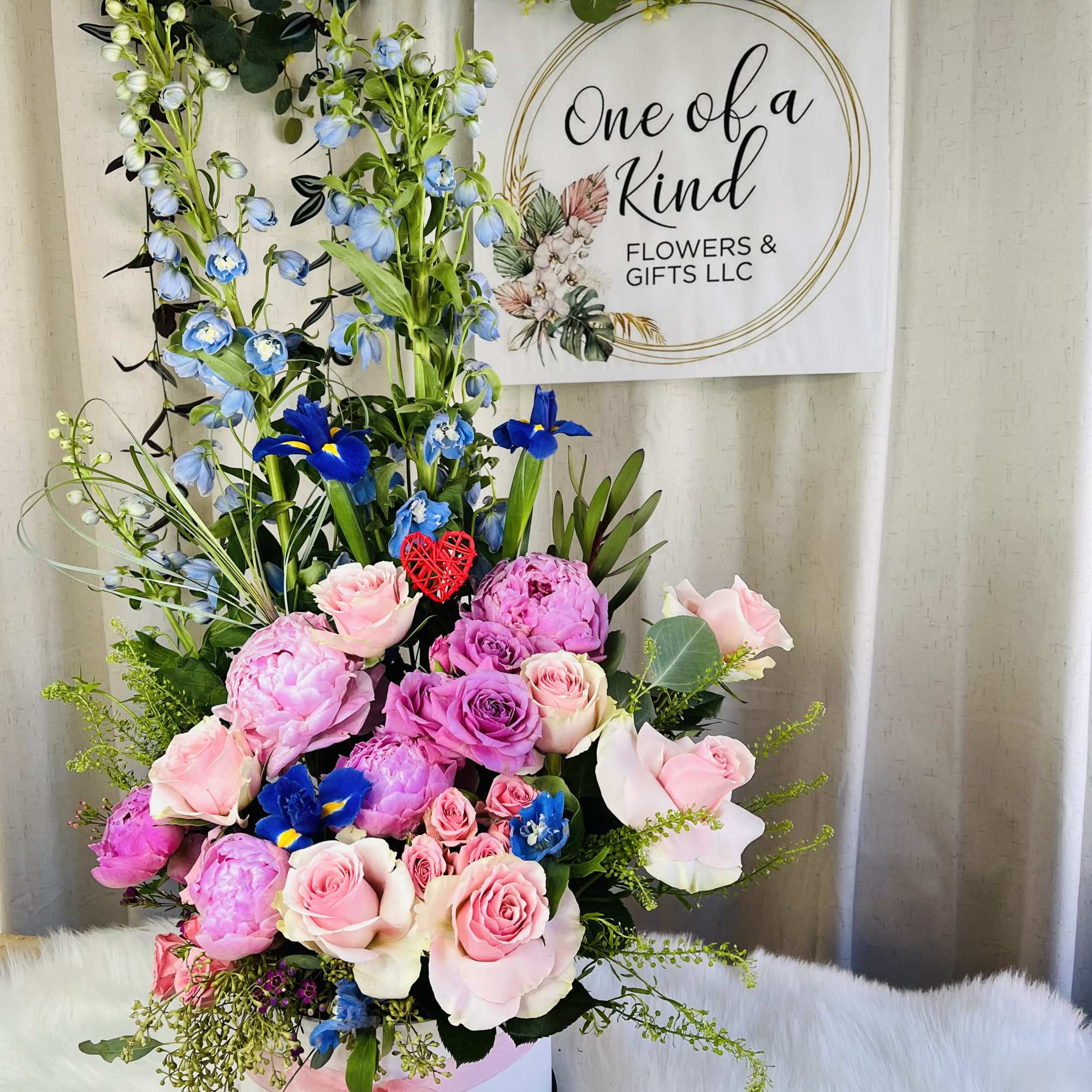 Tall pink and blue floral arrangement in a white hat box