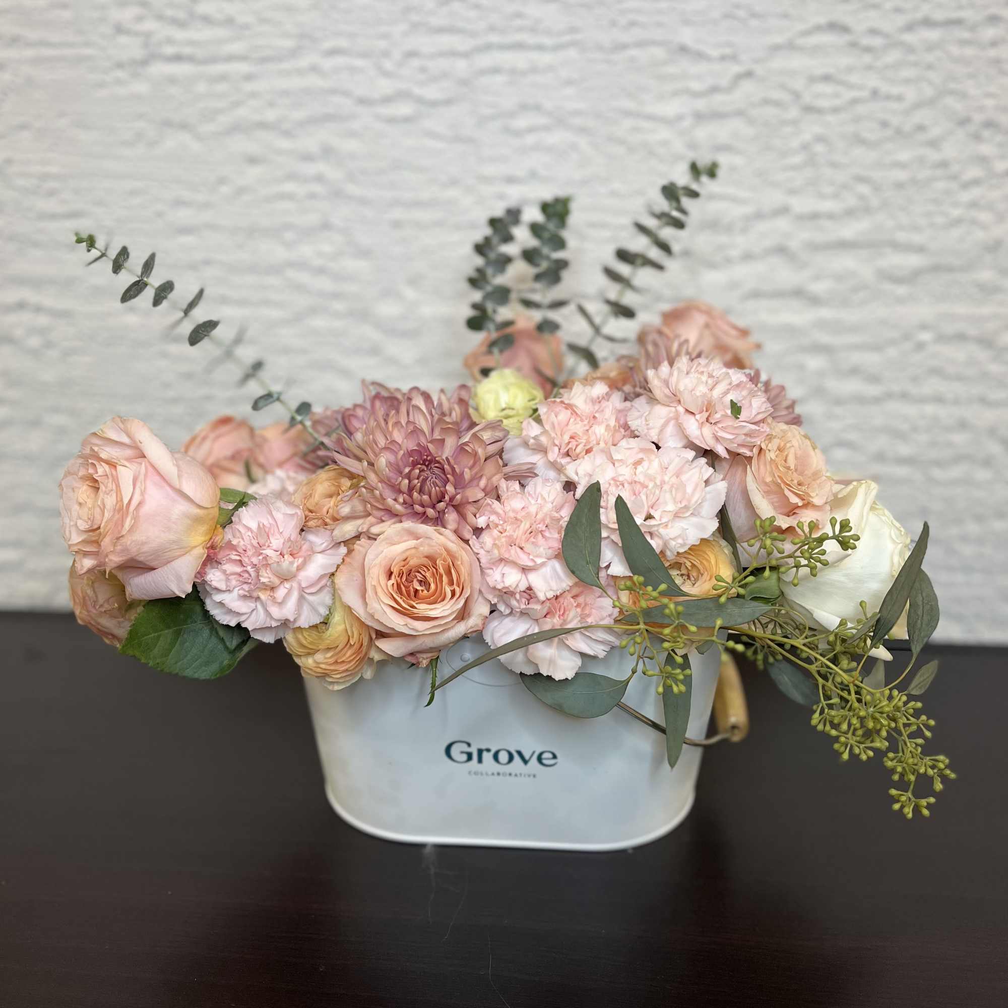 Pastel bouquet of roses, carnations, and mums in a white container