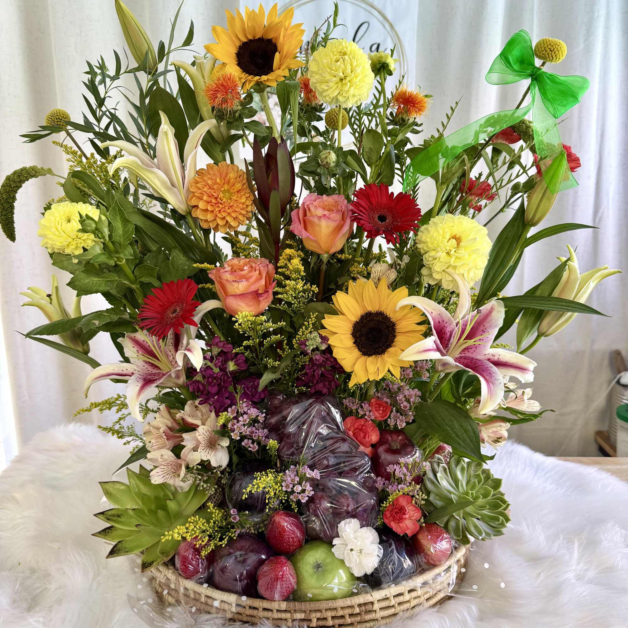 Mixed flower basket with sunflowers, lilies, roses, and fruit