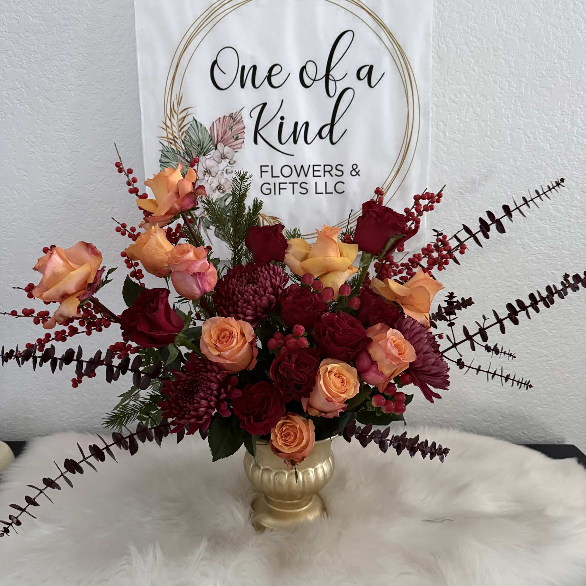 Mixed rose arrangement in a gold vase with red berry accents