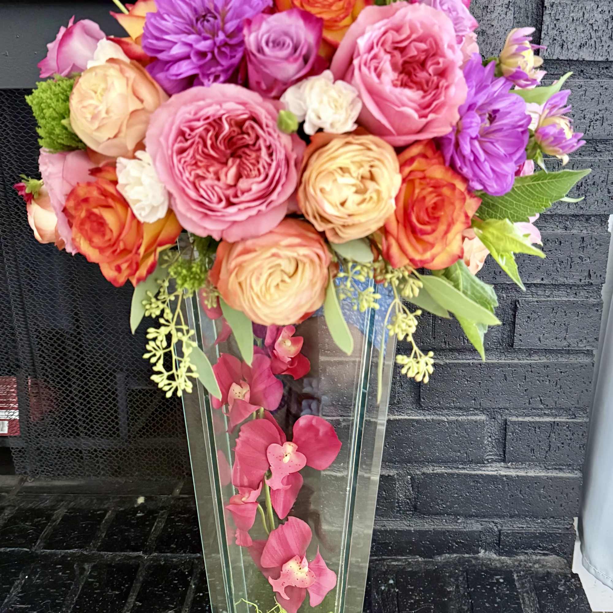Colorful bouquet of roses and dahlias in a tall glass vase