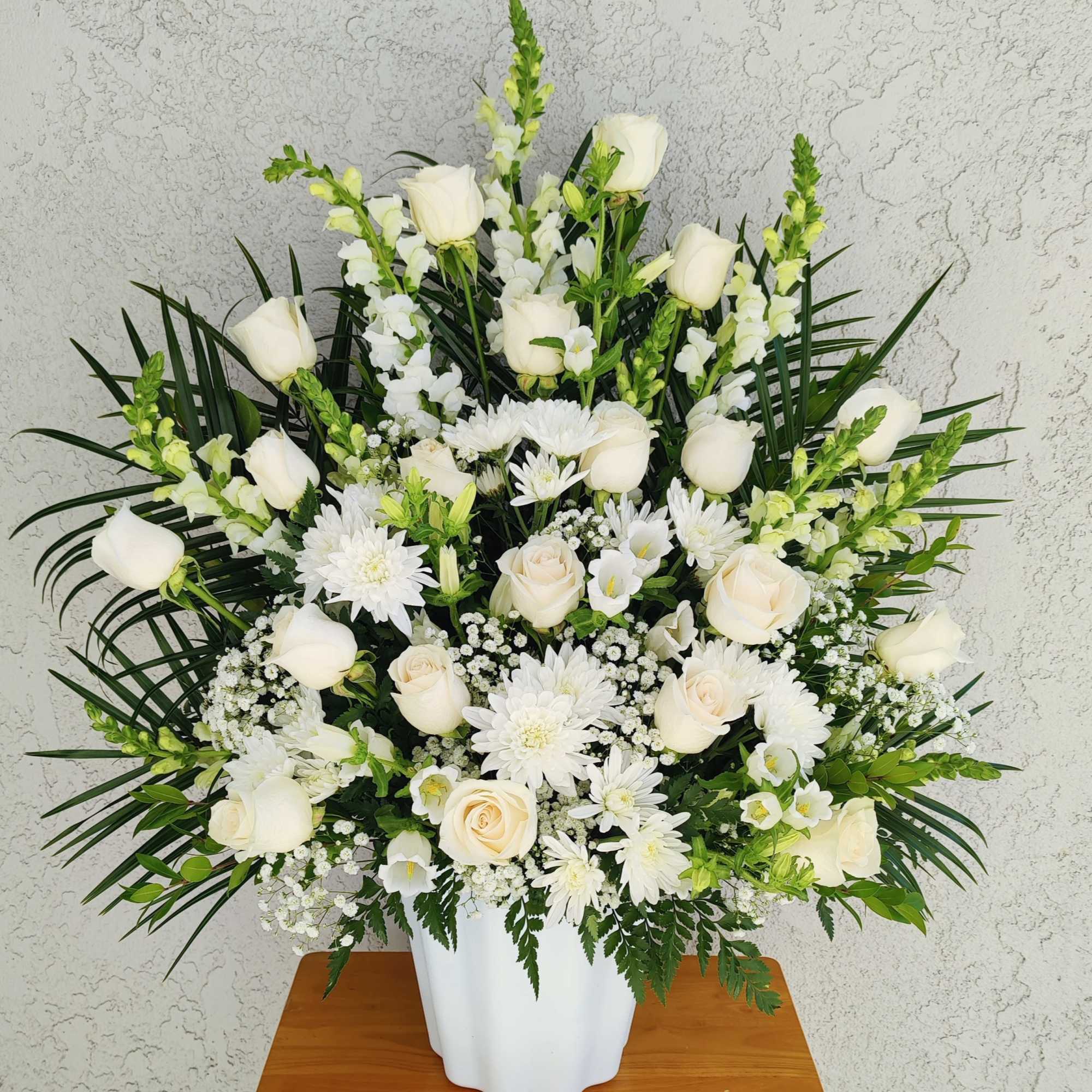 White roses and daisies arranged in a white vase