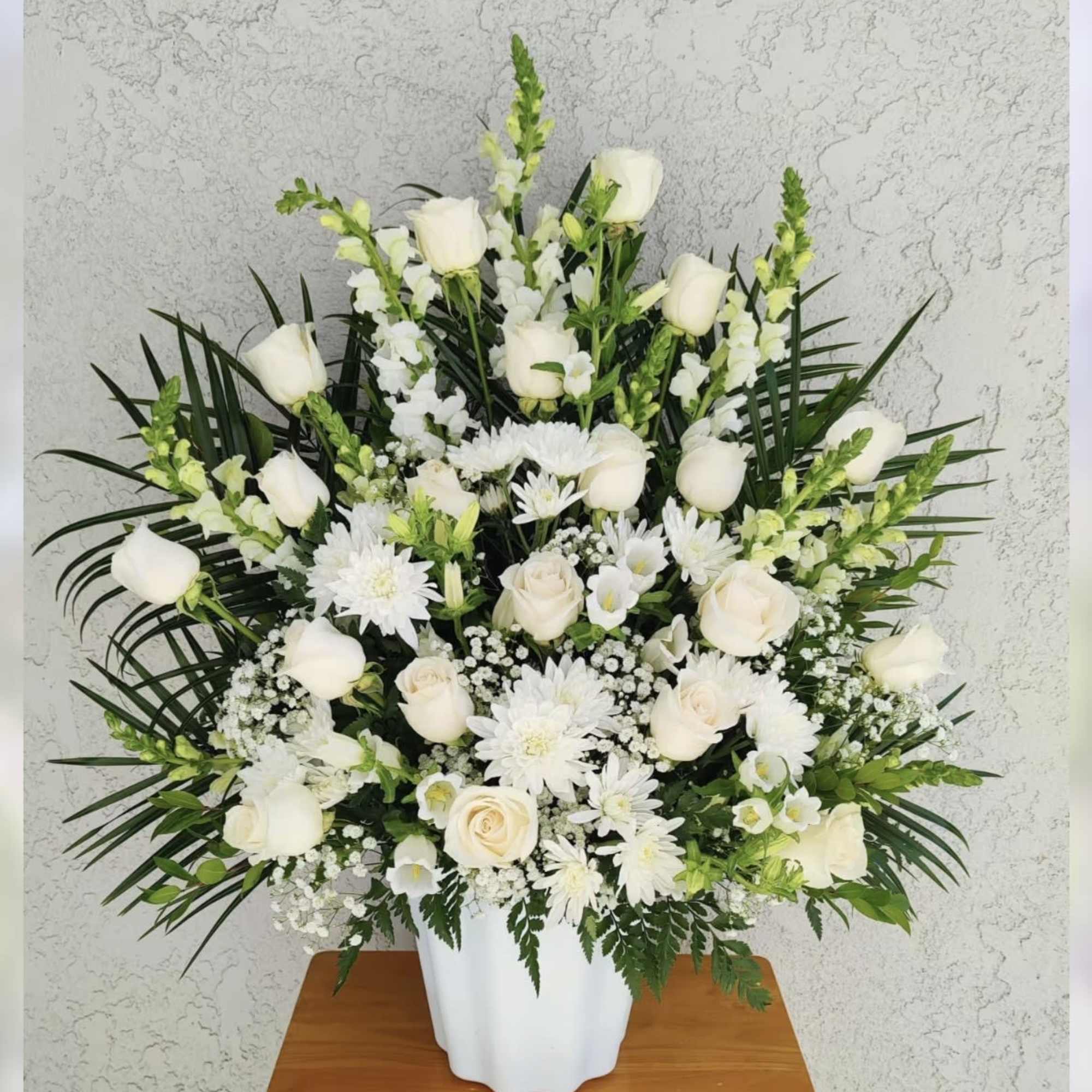 White roses and daisies arranged in a white vase