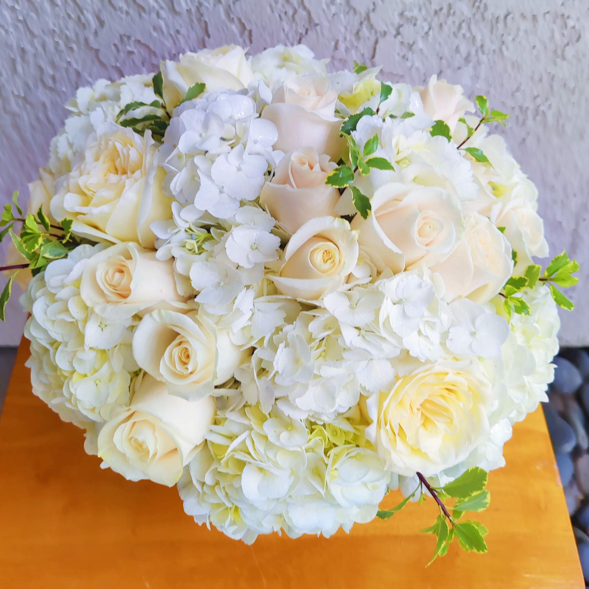Round bouquet of white roses and hydrangeas with small green accents