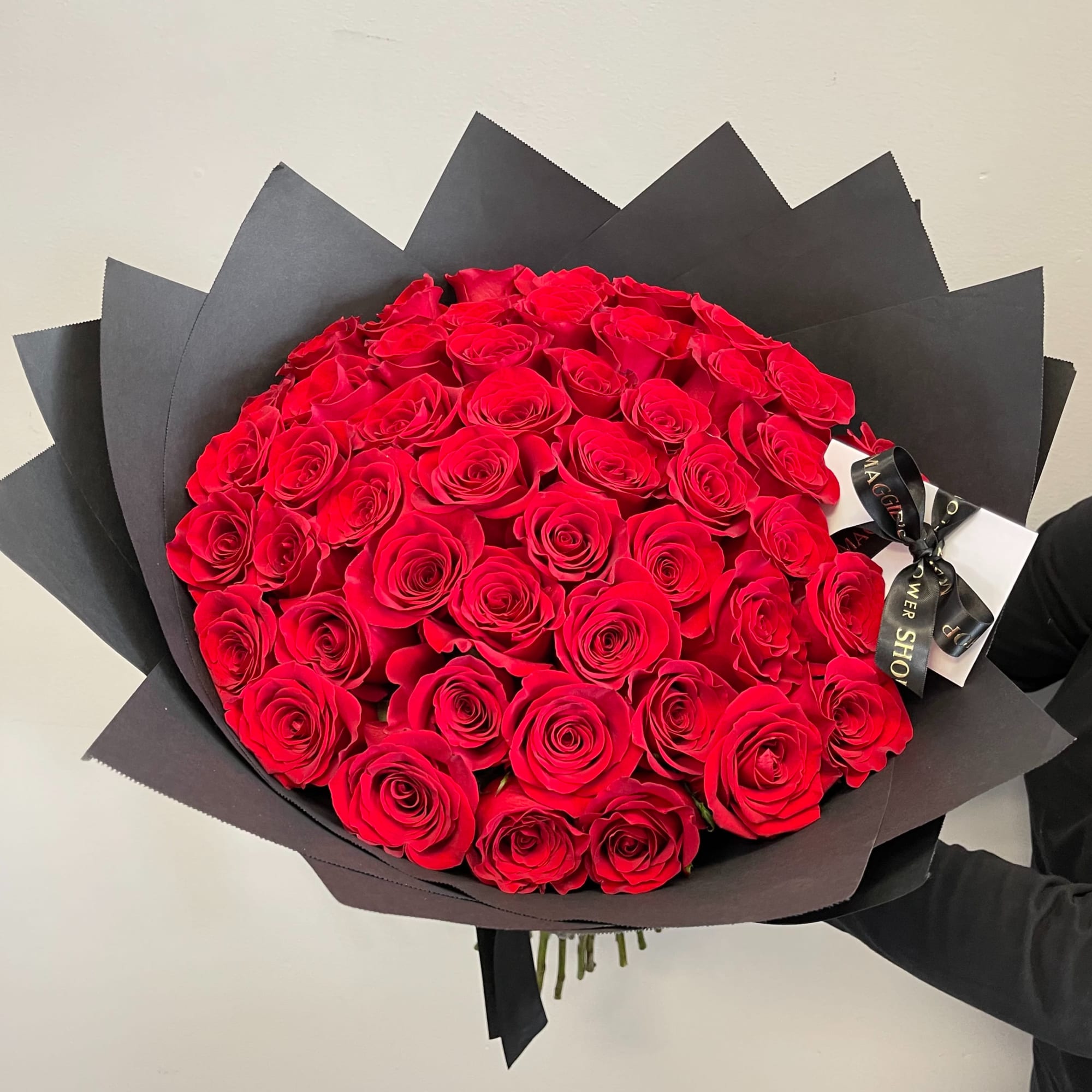 Large bouquet of red roses wrapped in black paper with a ribbon