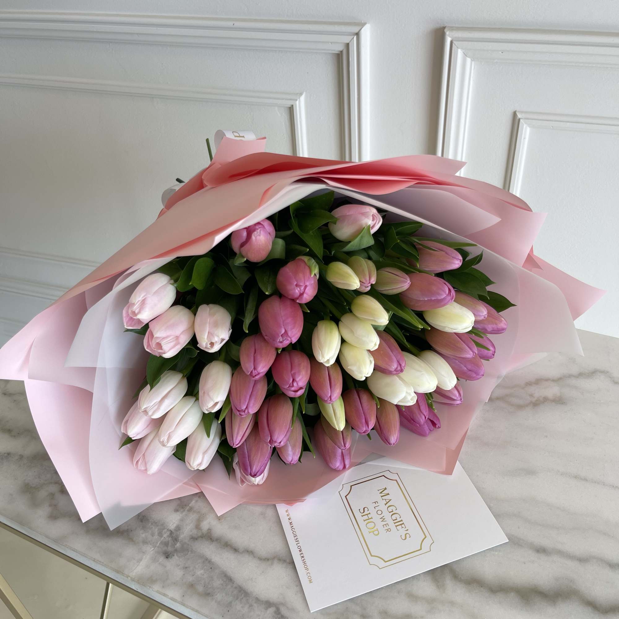 Bouquet of pink, white, and purple tulips wrapped in pink paper