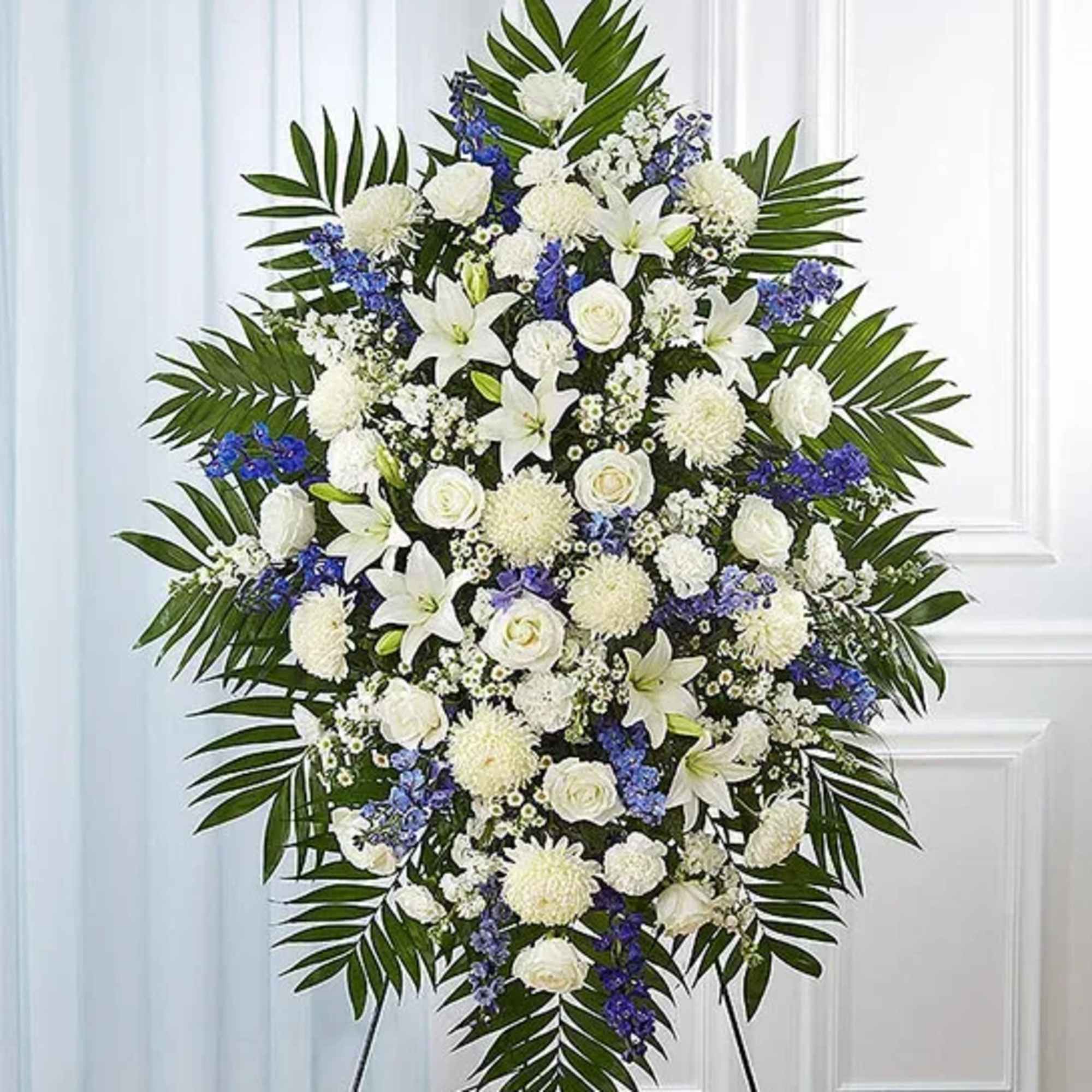 Standing floral spray of white lilies, roses, and blue flowers