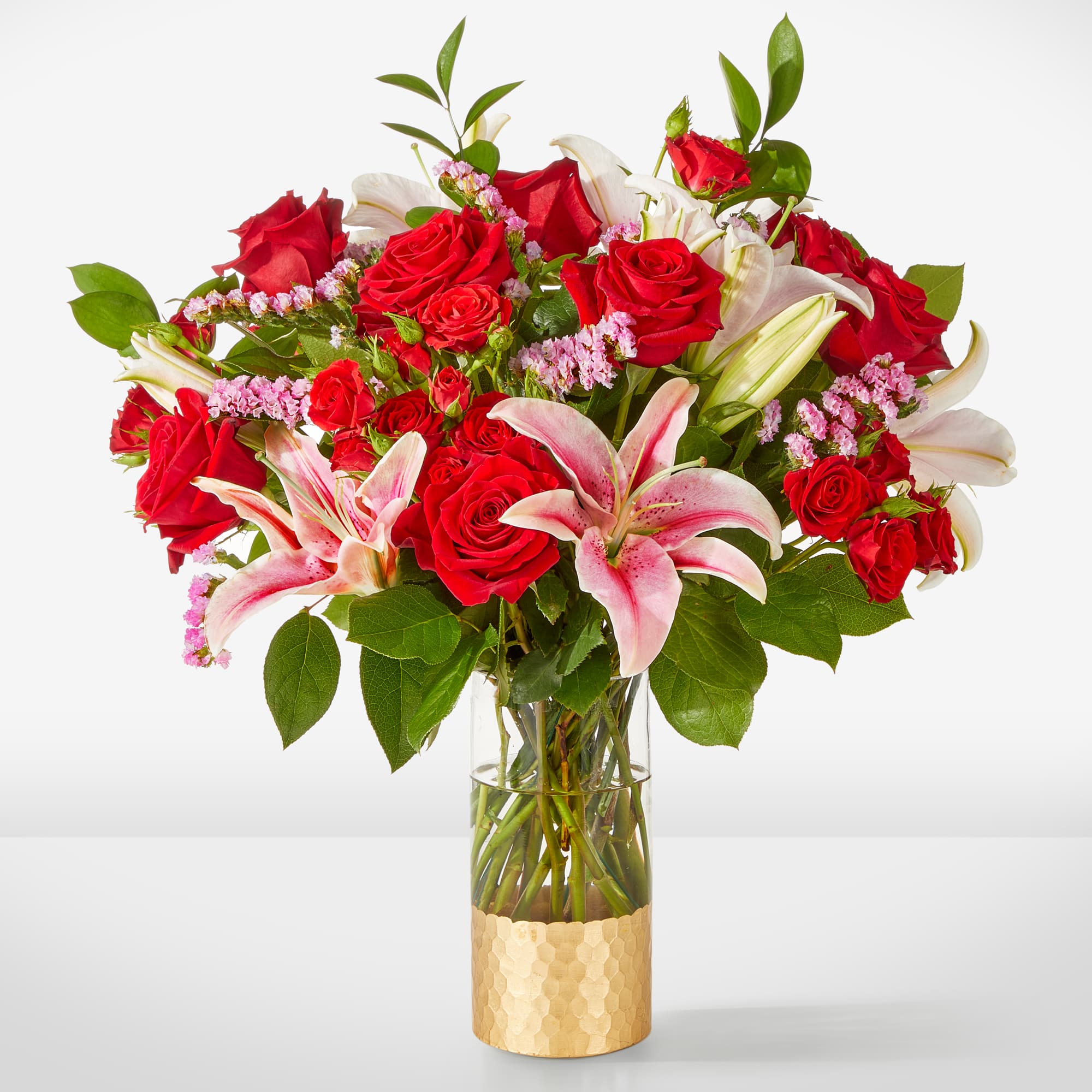 Bouquet of red roses and pink lilies in a clear glass vase