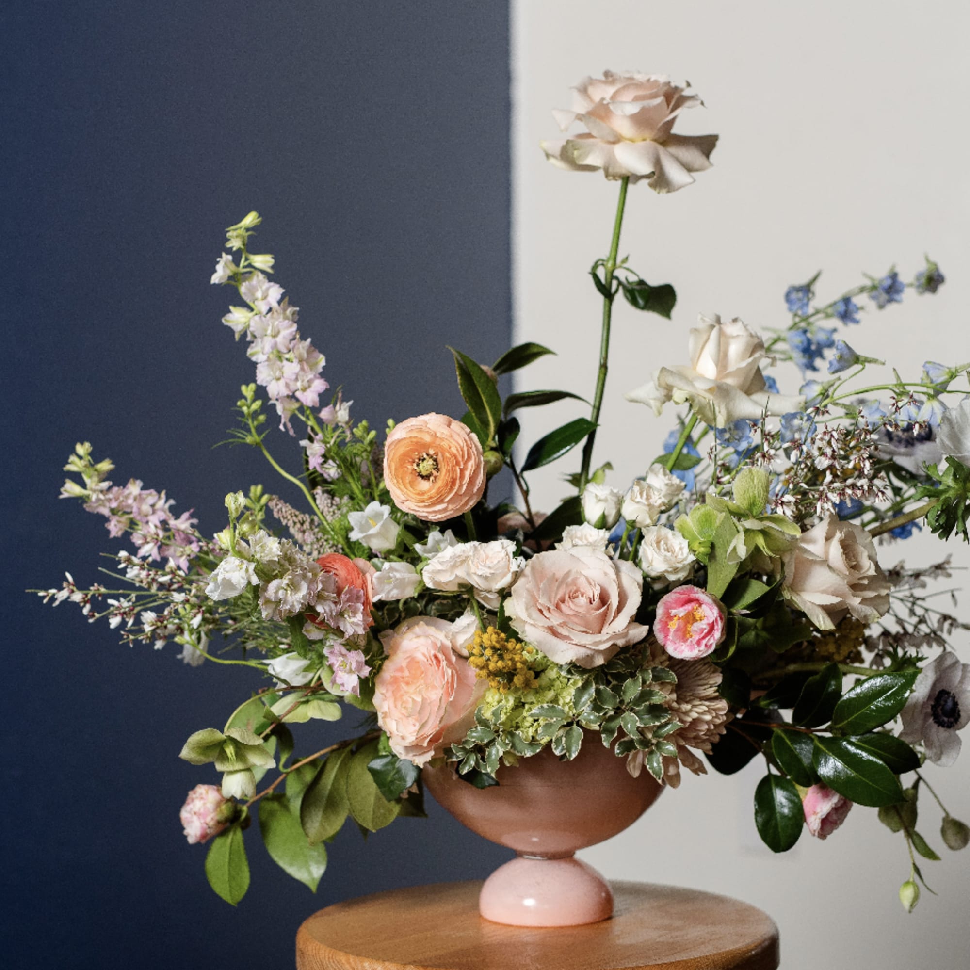 Mixed floral arrangement in a pink pedestal vase with pastel blooms