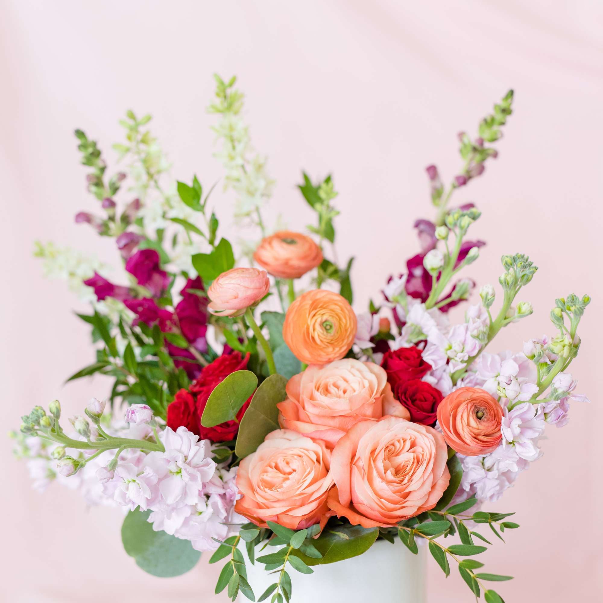 Mixed bouquet of peach and red flowers in a round box