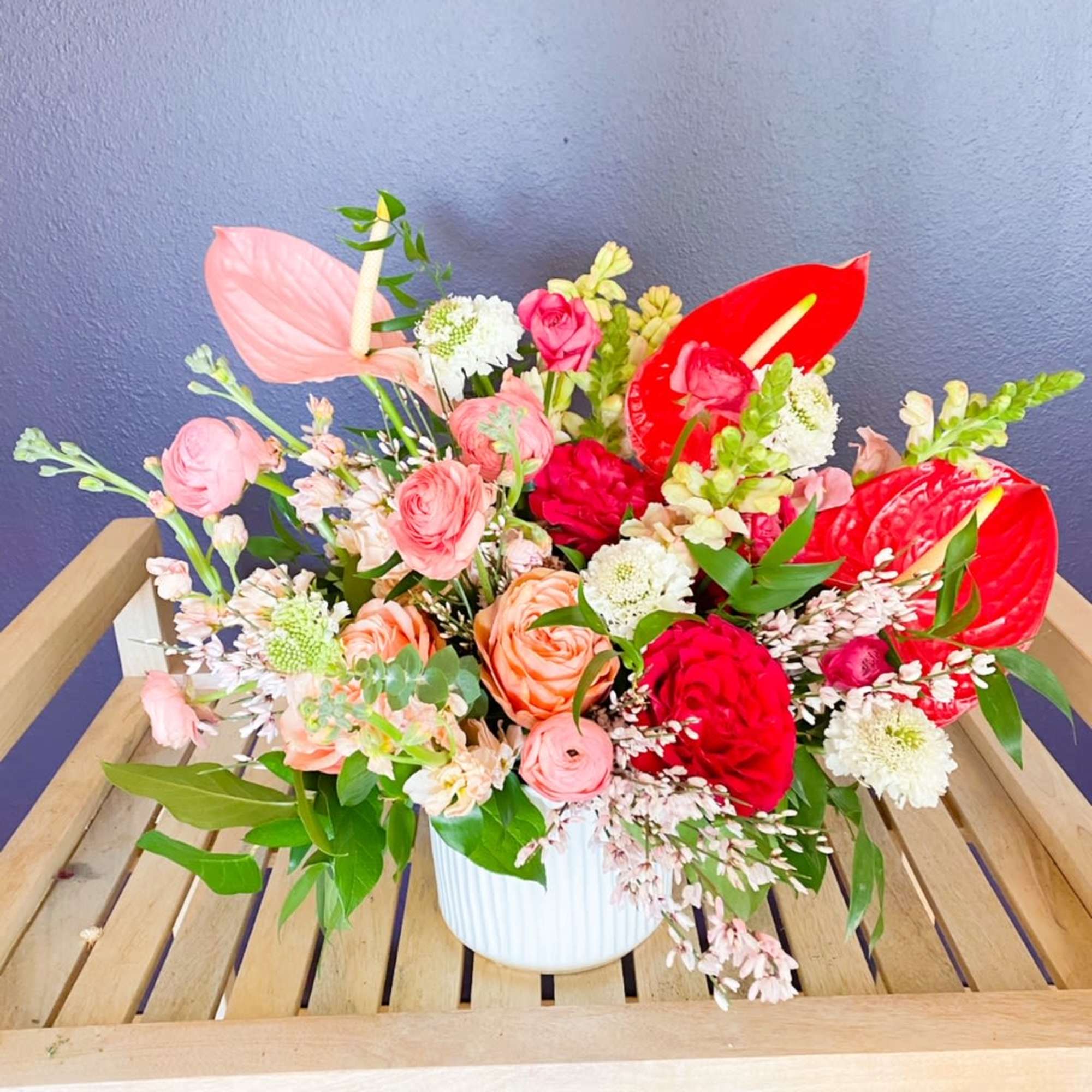 Mixed bouquet with pink and red blooms in a white vase