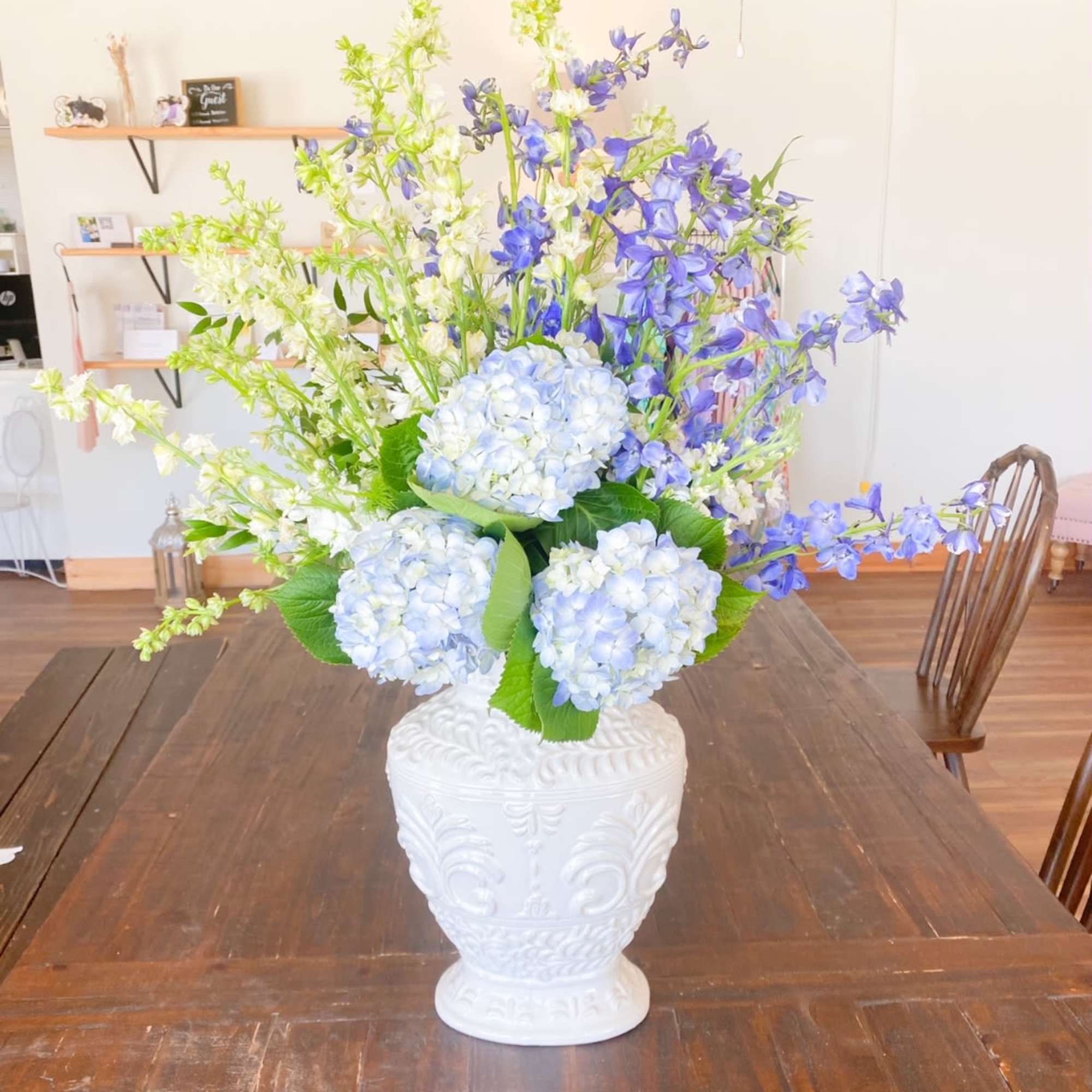 Blue and white floral arrangement in a white decorative vase