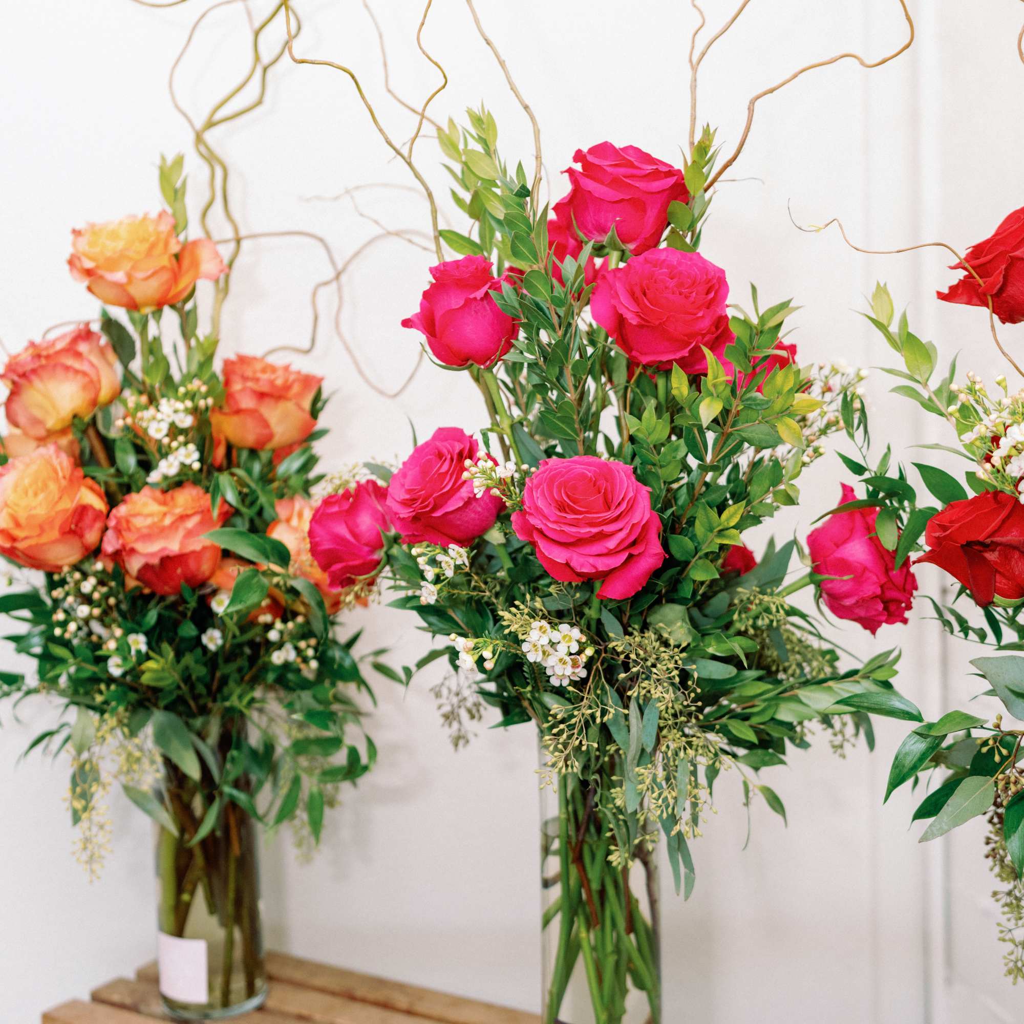Tall rose arrangements in glass vases with curly branches