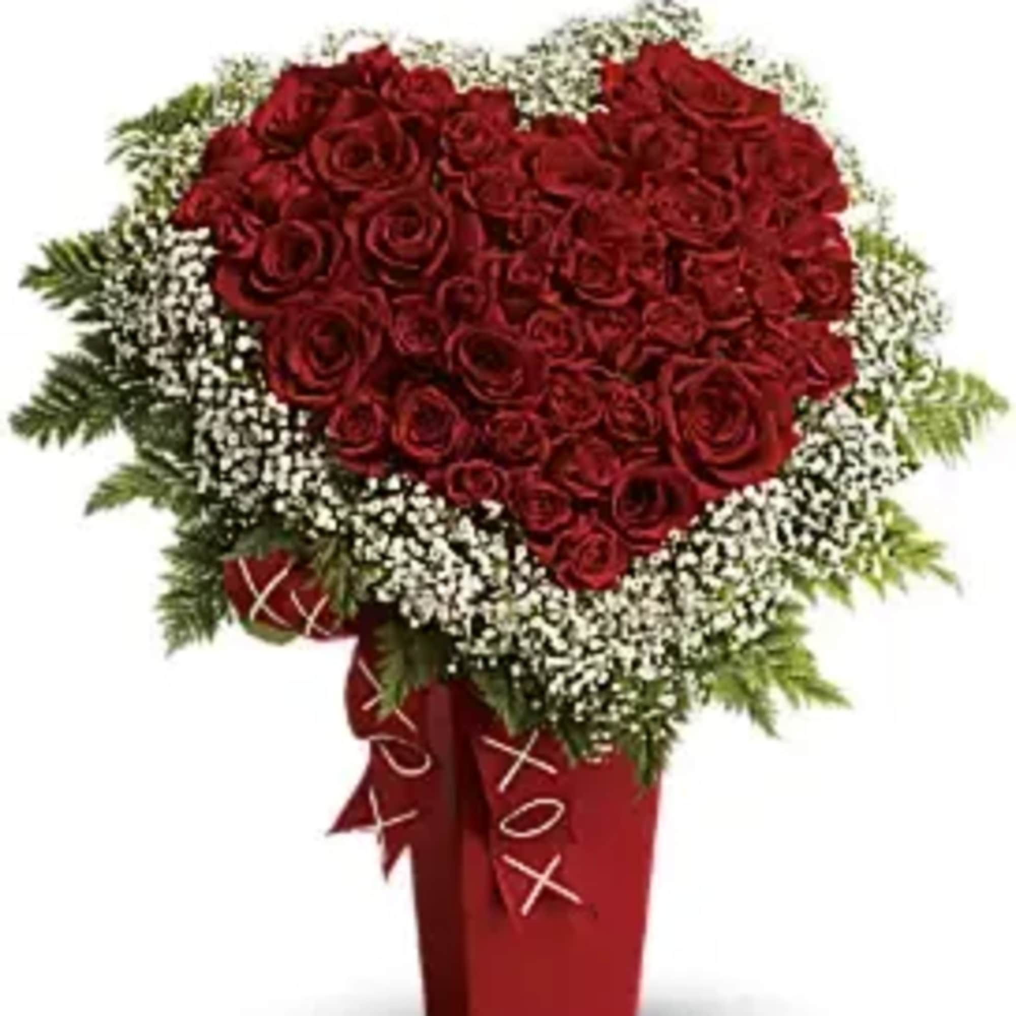 Heart-shaped red rose arrangement in a red vase with white filler flowers