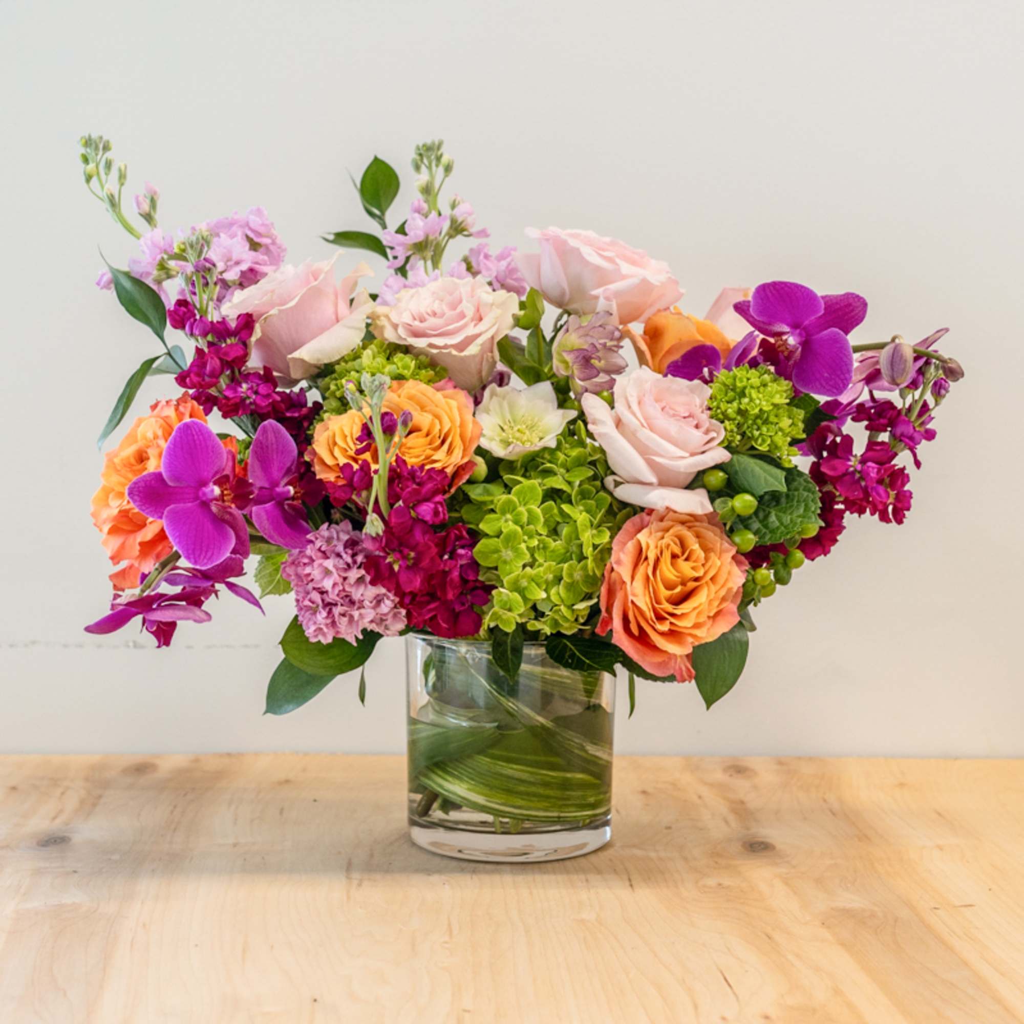 Mixed pink, orange, and purple flowers in a clear glass vase