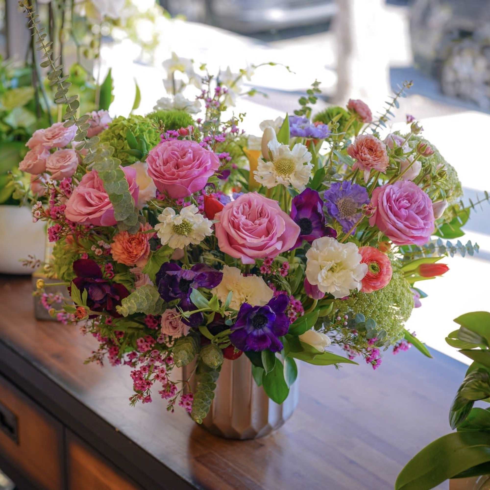 A luxurious garden-style flower arrangement featuring soft pink roses, delicate seasonal blooms