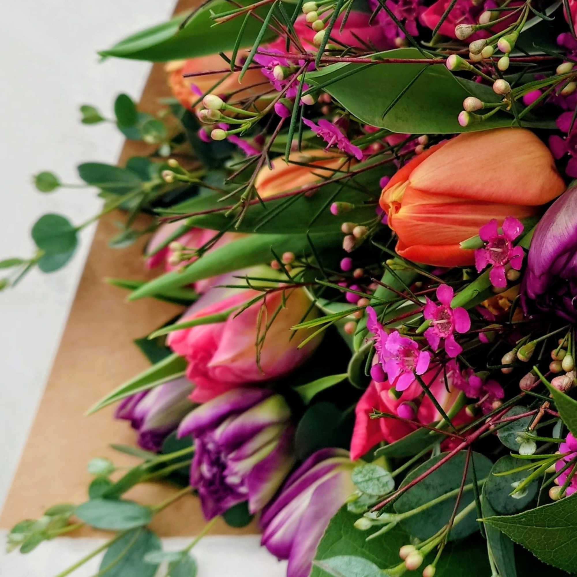 Close-up bouquet of pink, orange, and purple tulips with small magenta filler flowers