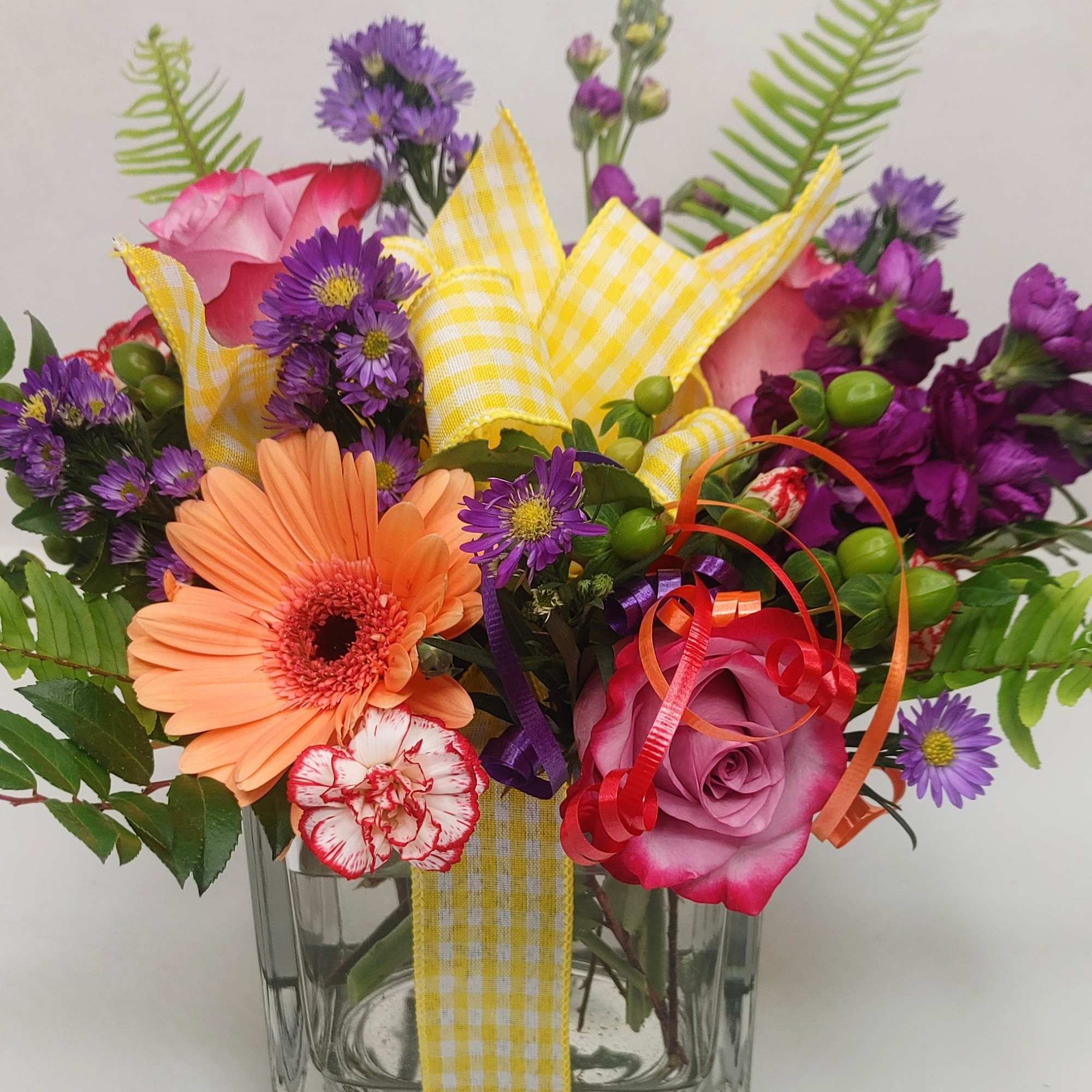 Mixed bouquet in a clear glass vase with pink, purple, and peach flowers