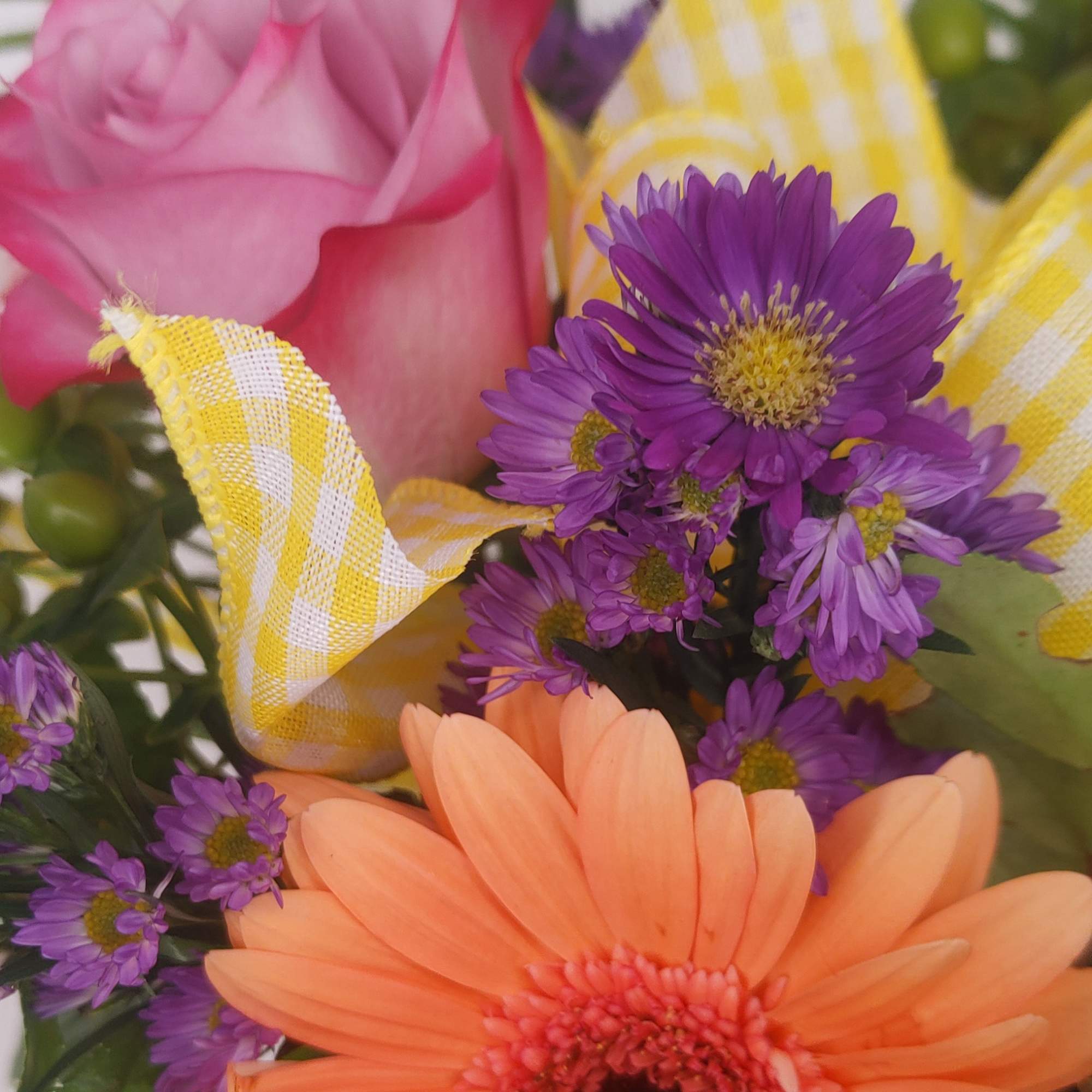 Pink rose with purple daisies and an orange gerbera daisy