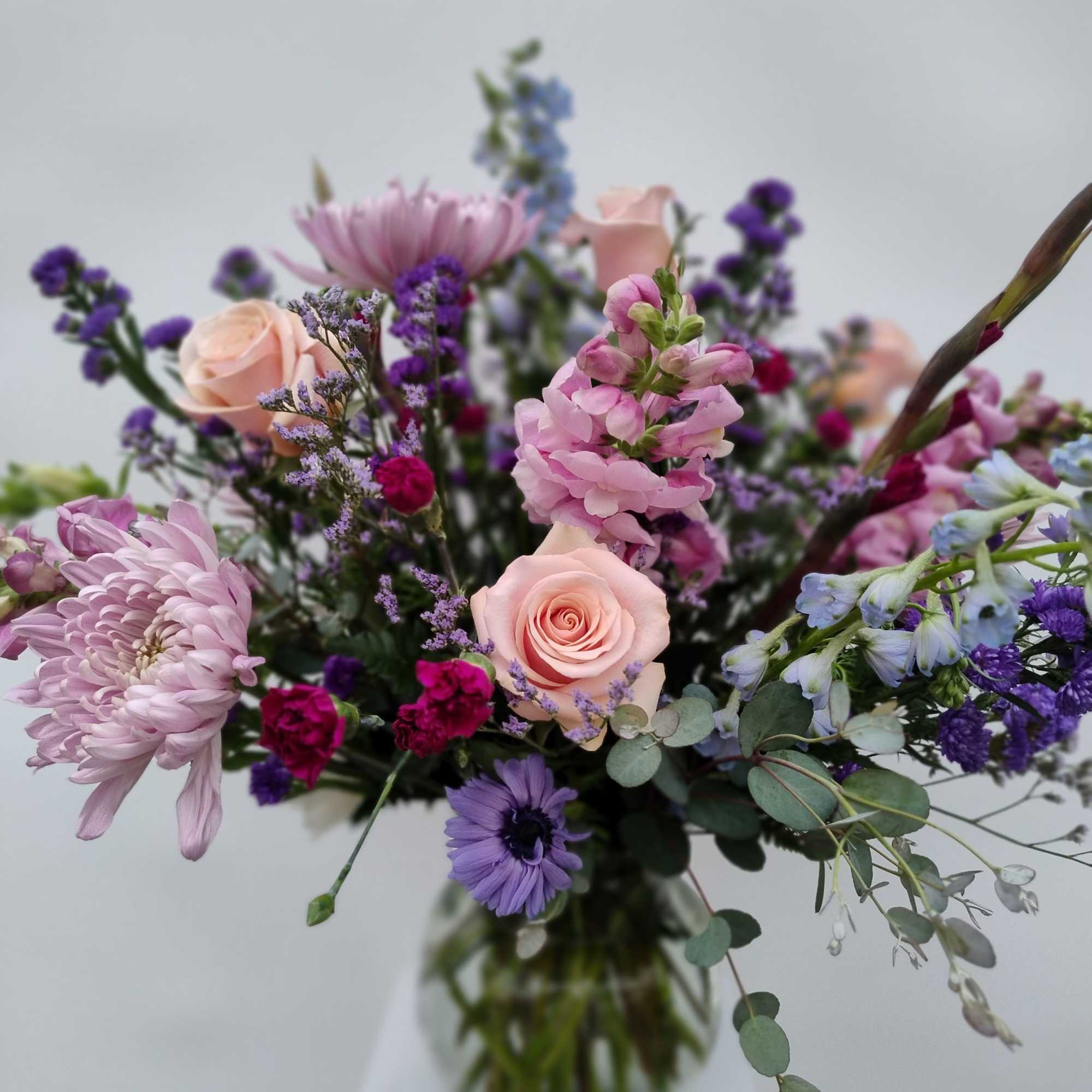 Mixed bouquet of pink and purple flowers in a glass vase