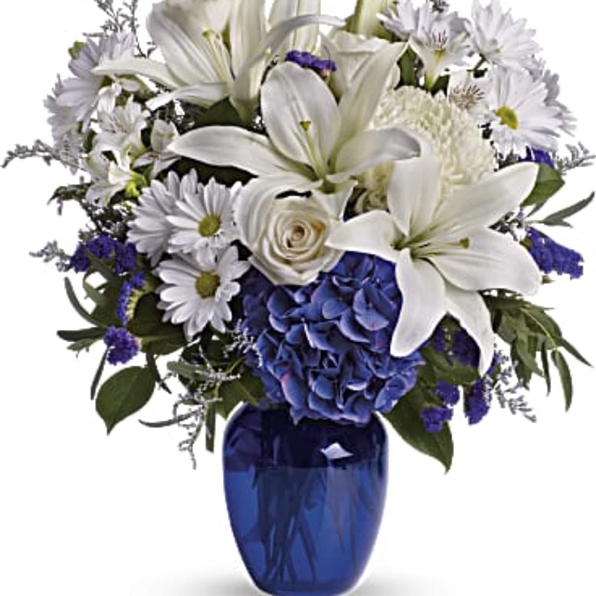 White lilies and daisies with blue hydrangea in a blue vase