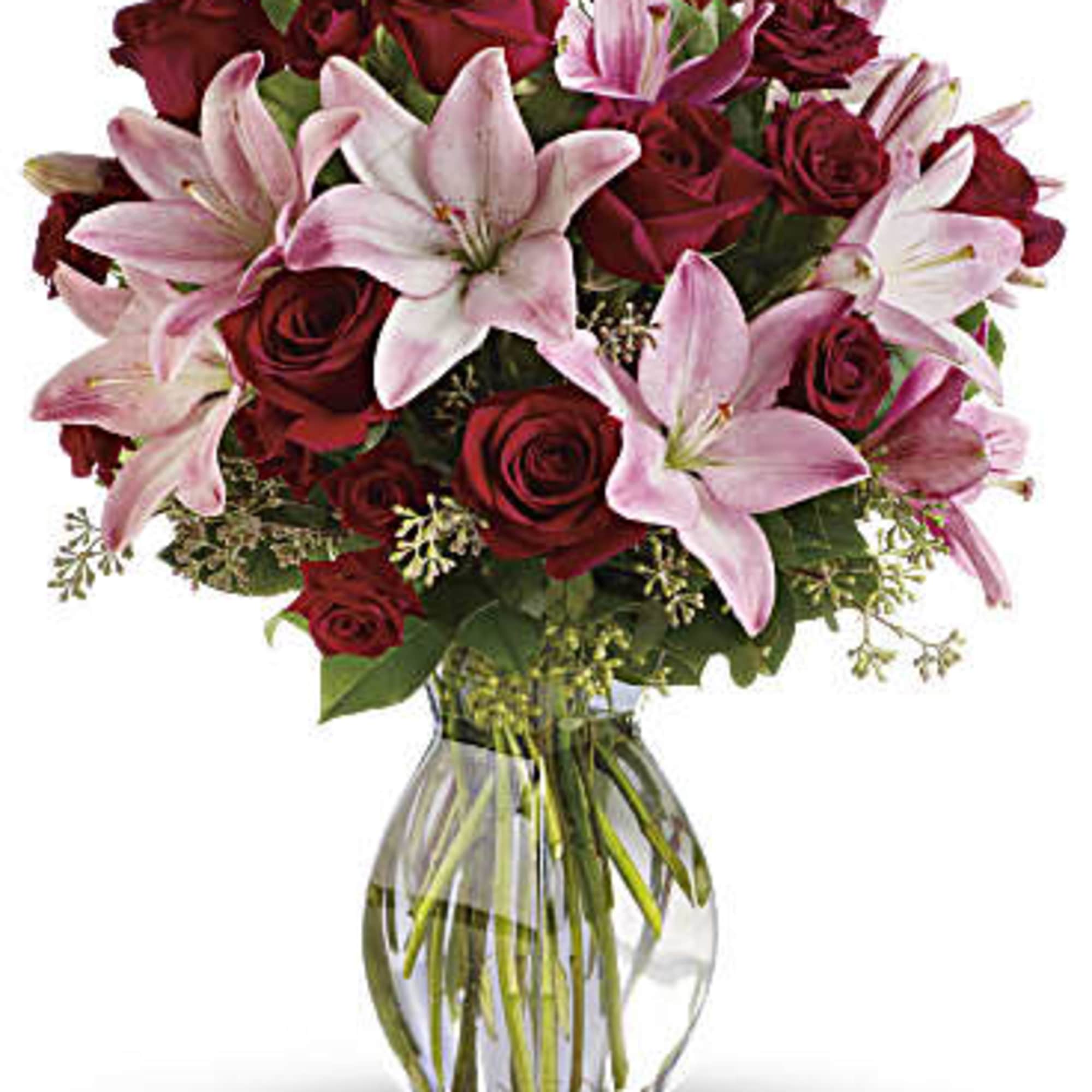 Bouquet of red roses and pink lilies in a clear glass vase