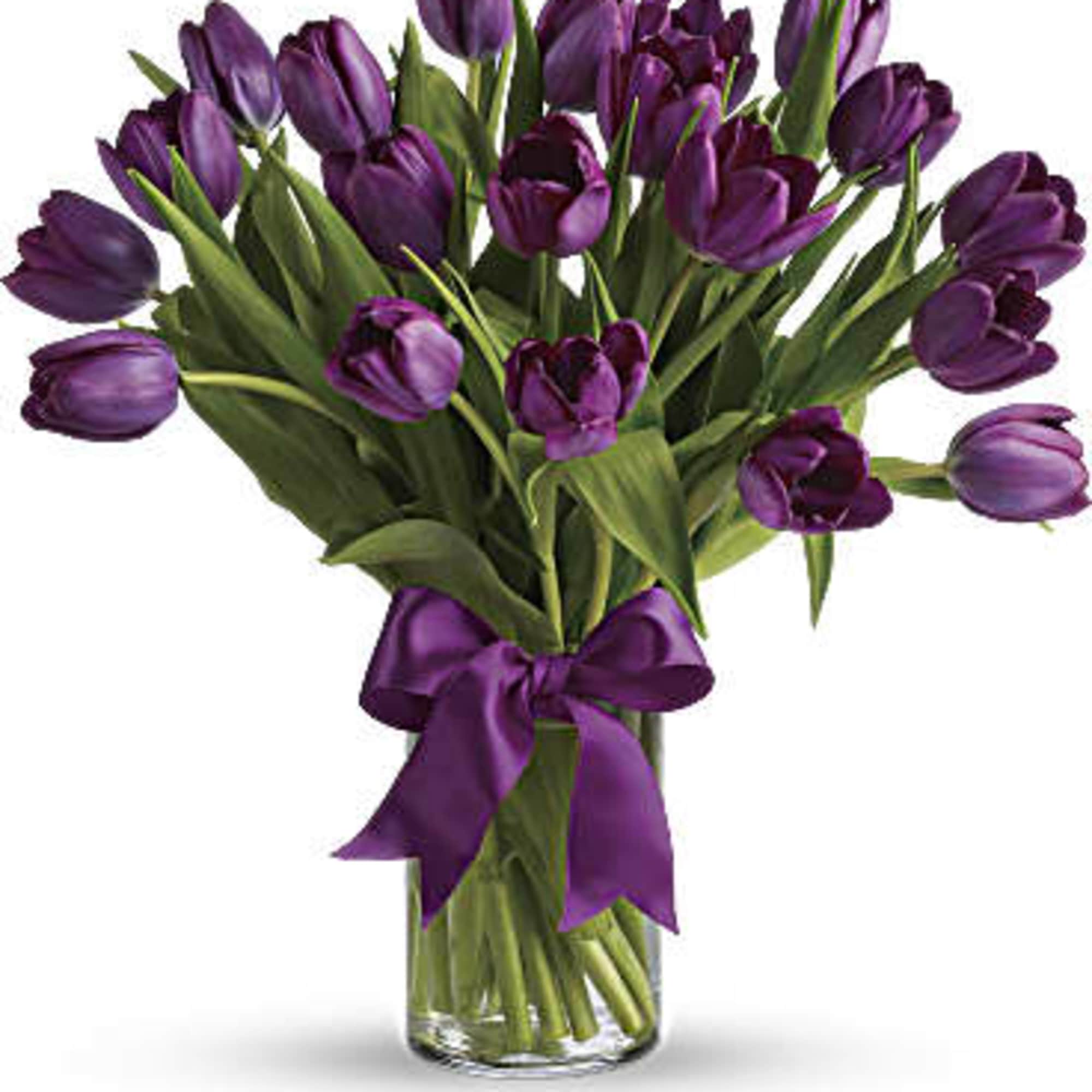 Purple tulip bouquet in a clear glass vase with a purple ribbon