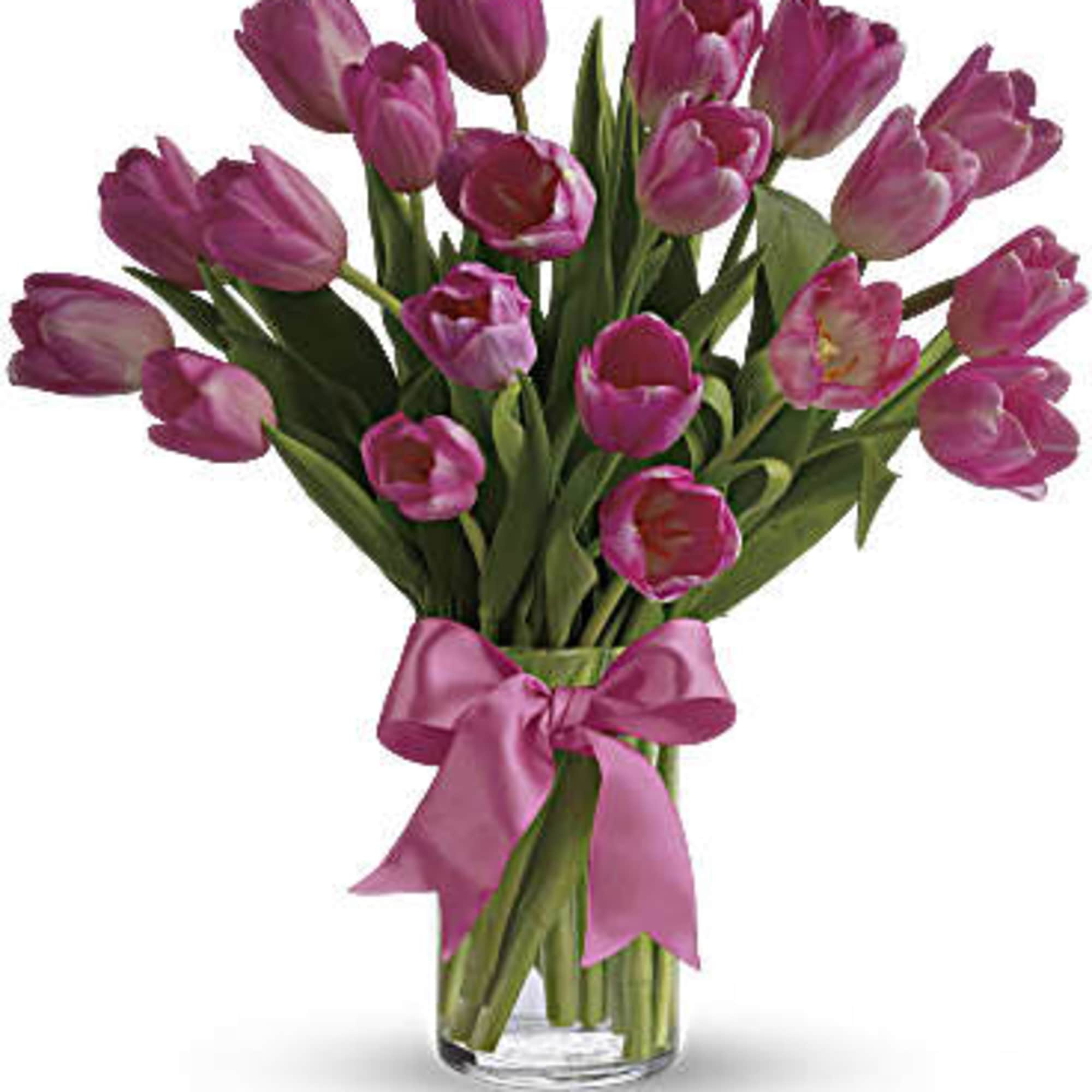 Bouquet of pink tulips in a clear glass vase with a pink ribbon
